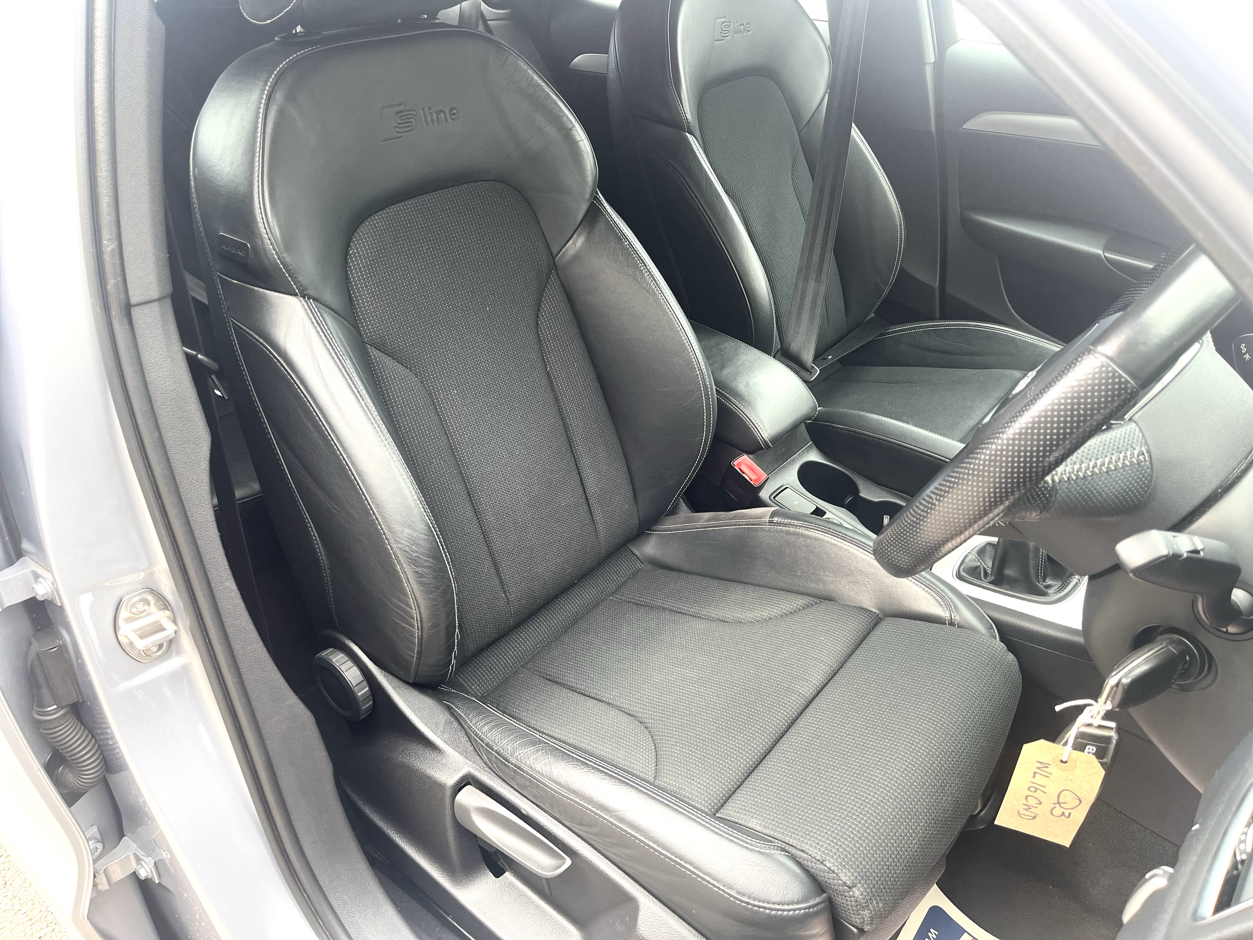 The interior of a car showing black leather front seats with 'S line' branding on the headrests, a center console, and part of the dashboard.