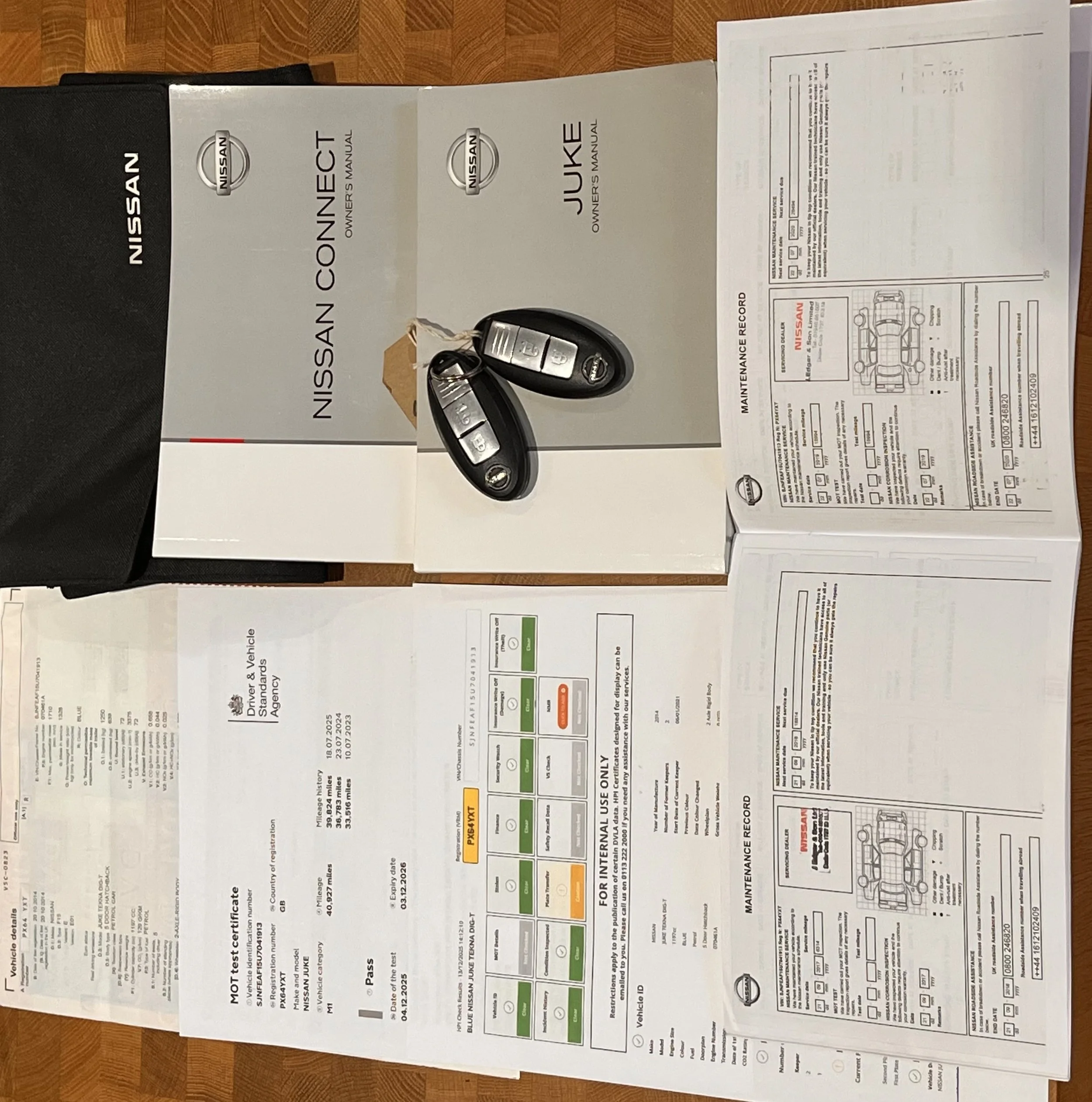 Car keys placed on a Nissan owner’s manual, with other vehicle documents laid out on a table.