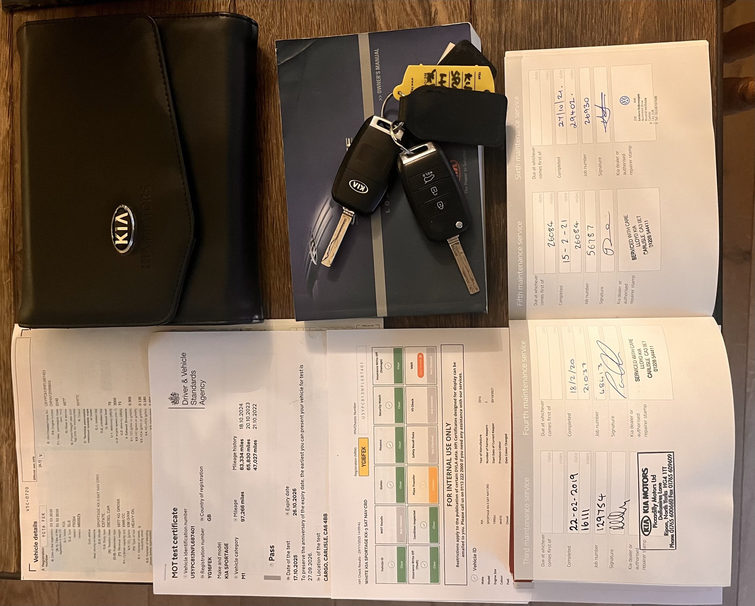 Kia vehicle service records and keys on a wooden table.