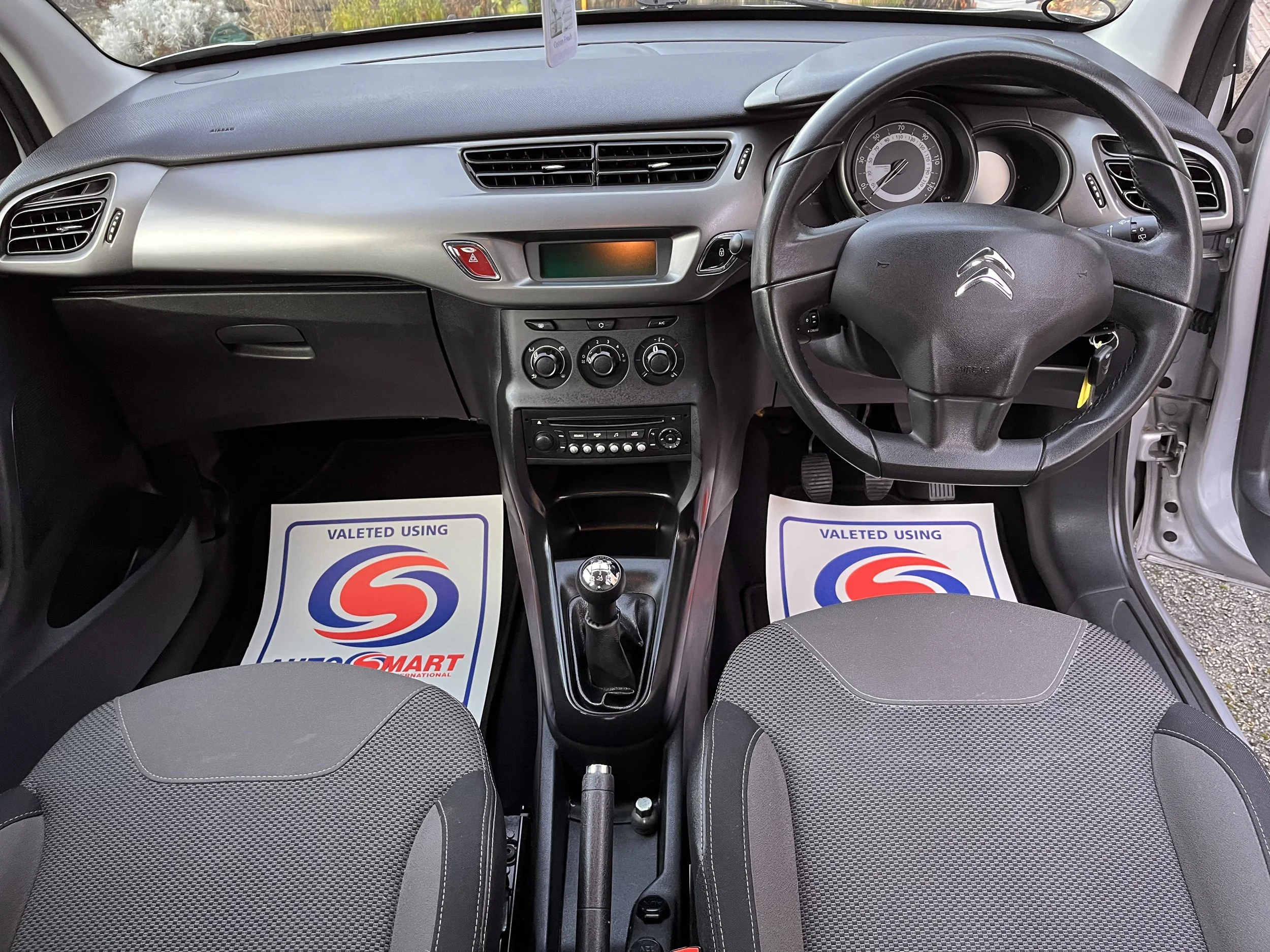 Interior of a Citroën car showing the dashboard, steering wheel, gear shift, and front seats, with driver and passenger side floor mats branding 'Valeted Using Liqui Moly Smart'.