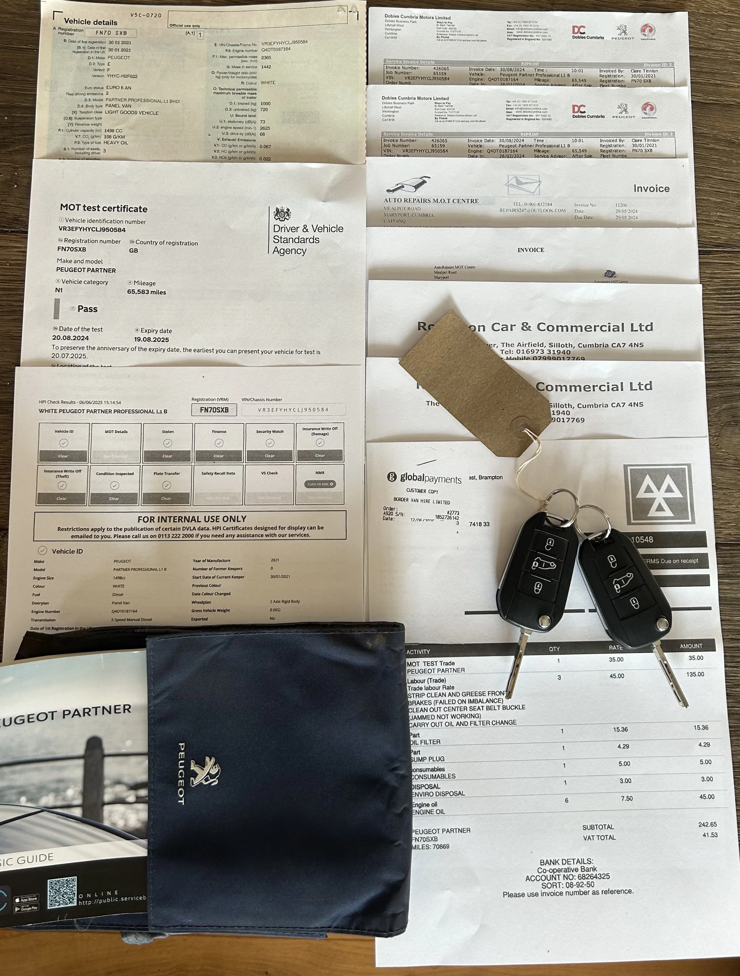 Car documents including registration, MOT certificate, invoices, keys, and a Peugeot pouch, all arranged on a wooden surface.