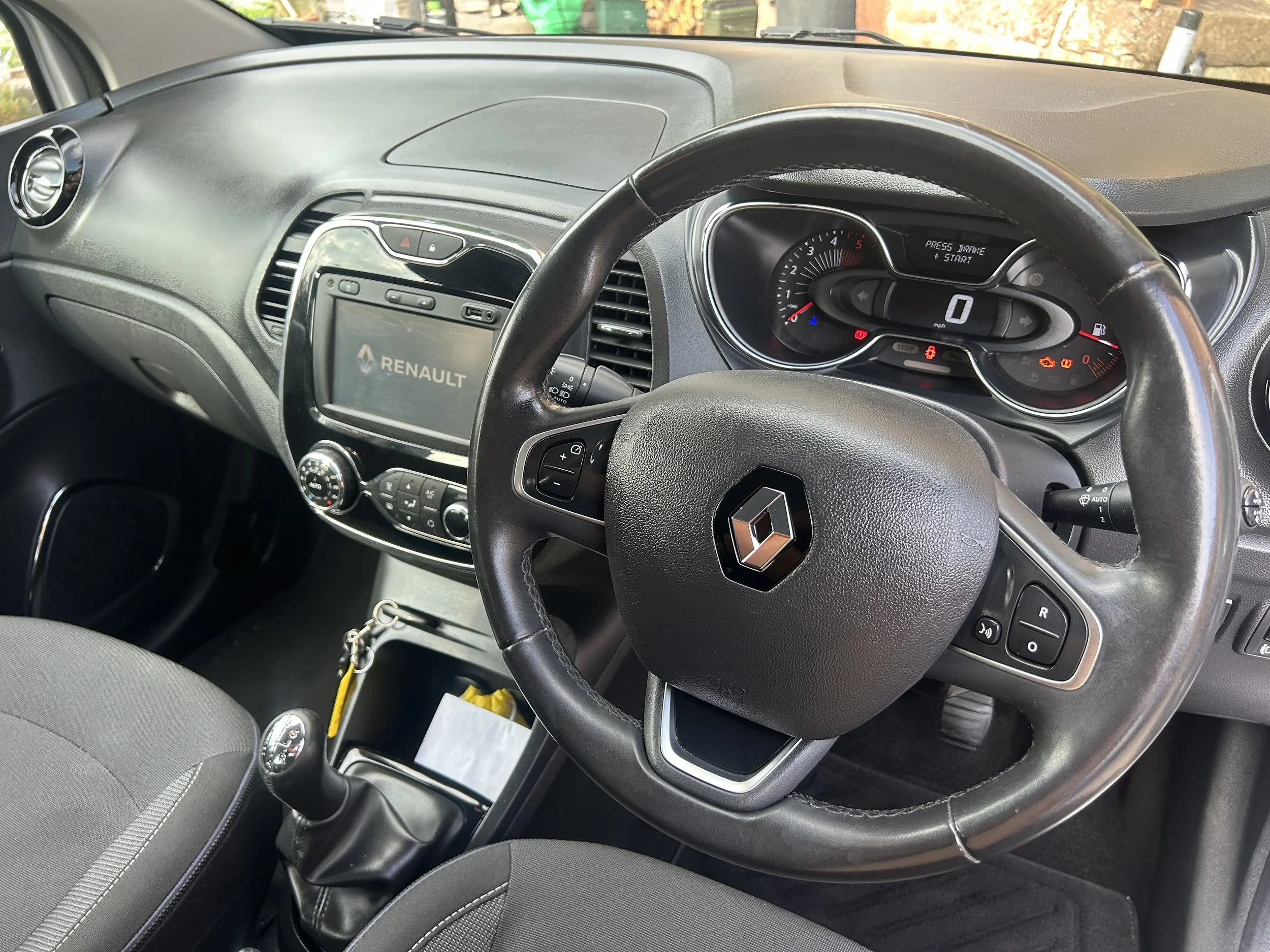 Interior of a Renault vehicle showing the dashboard, steering wheel, gear shifter, and central console with a Renault display.