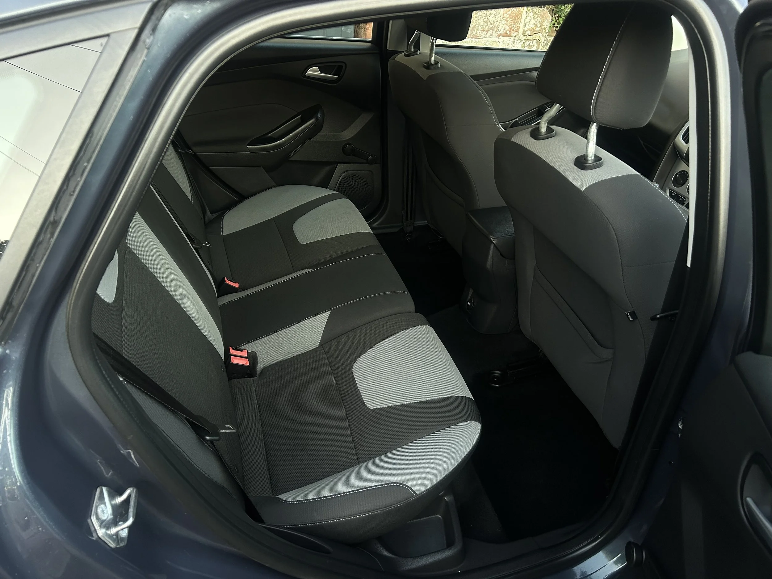Interior of a car showing the back seat, with black and gray fabric upholstery and black plastic trim.