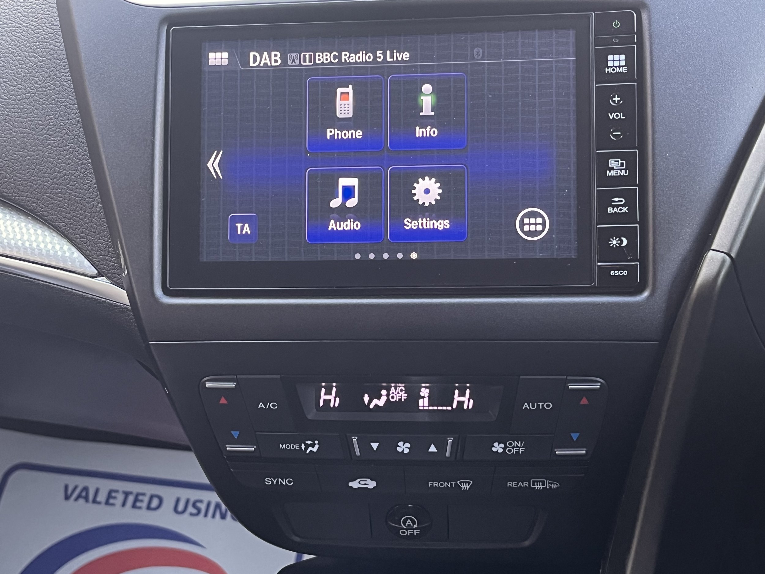 Car dashboard with touchscreen display showing entertainment options, and climate control settings below.