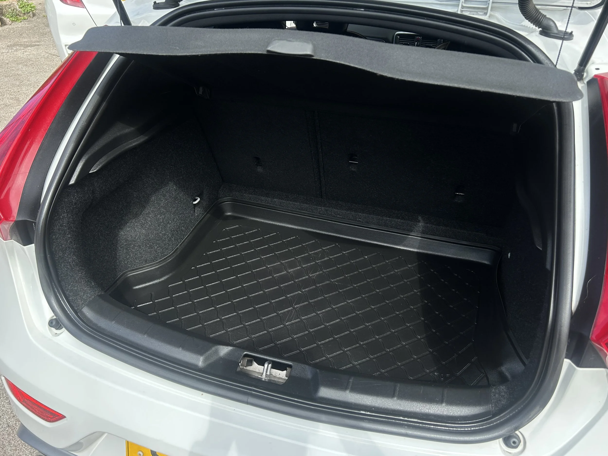 Open car trunk with black rubber mat, empty interior, and a parcel shelf at the top.