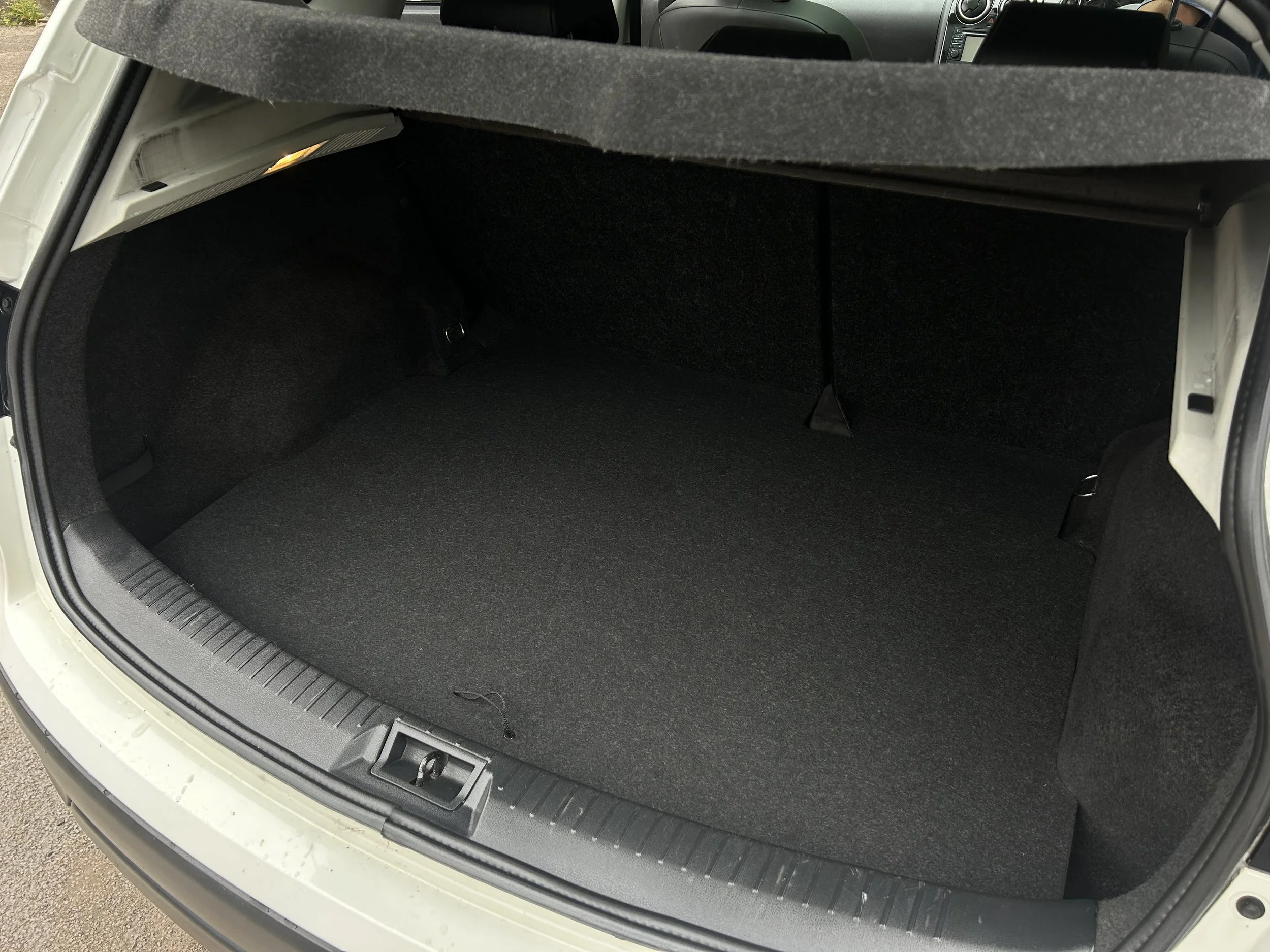 Open trunk of a car showing a spacious and empty cargo area with black interior lining.