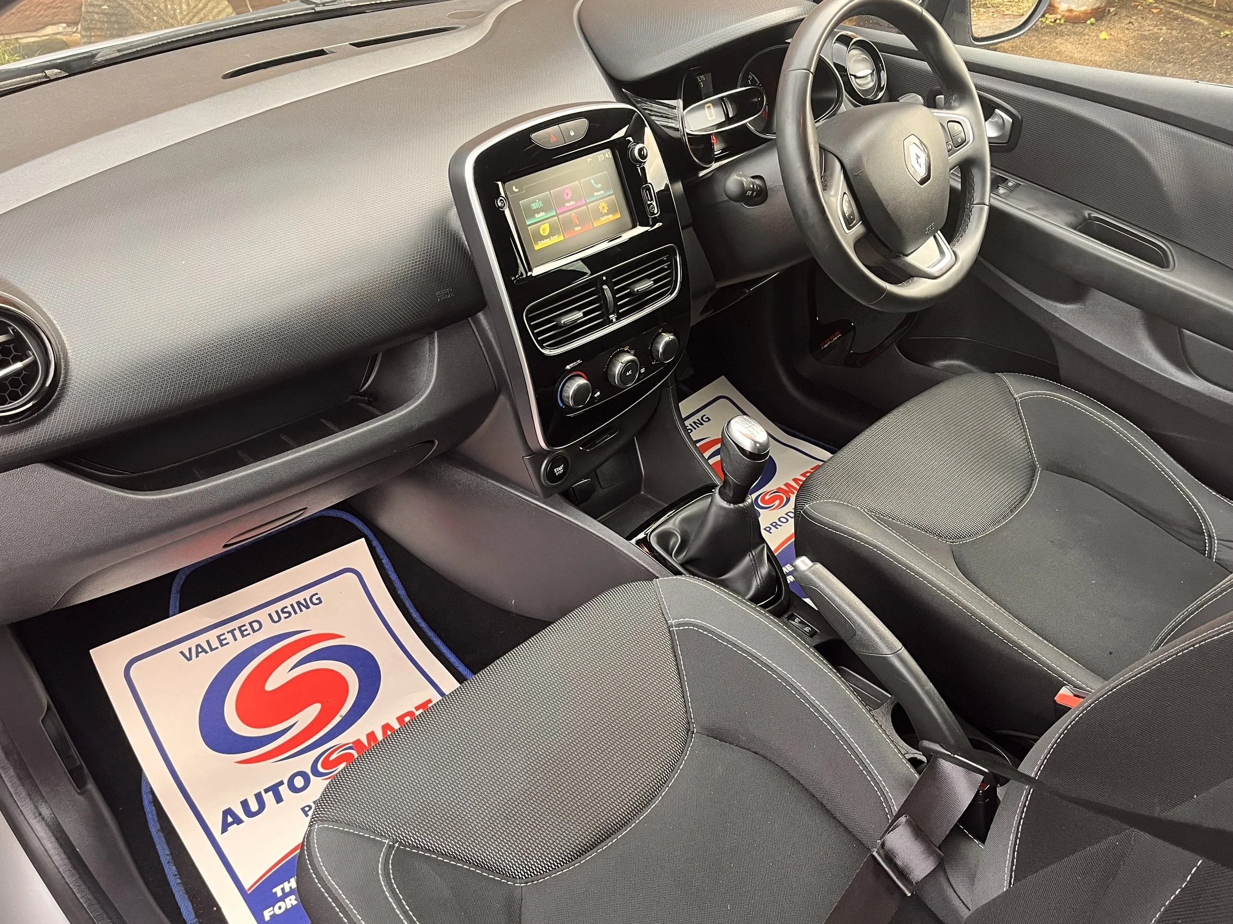 Interior of a car showing the dashboard, steering wheel, gear shift, front seats, and a touchscreen display in the center console.