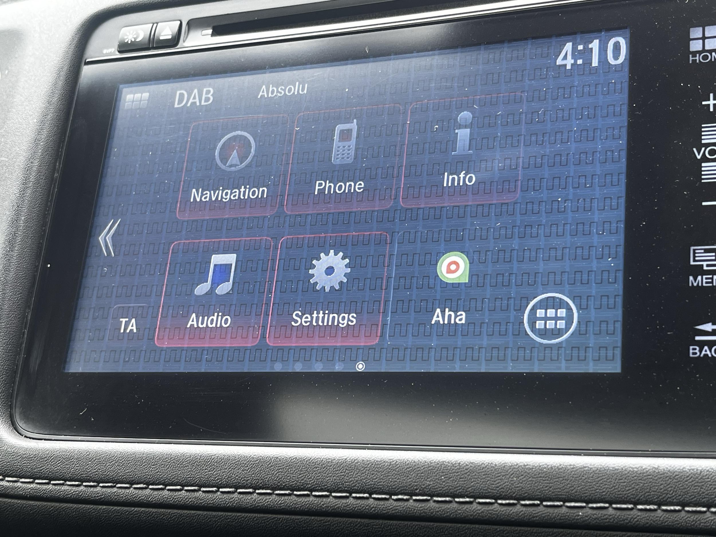 Car infotainment screen displaying radio options for DAB and Absolute, with menu icons for Navigation, Phone, Info, Audio, Settings, and Aha, along with a music note, gear, and other icons.