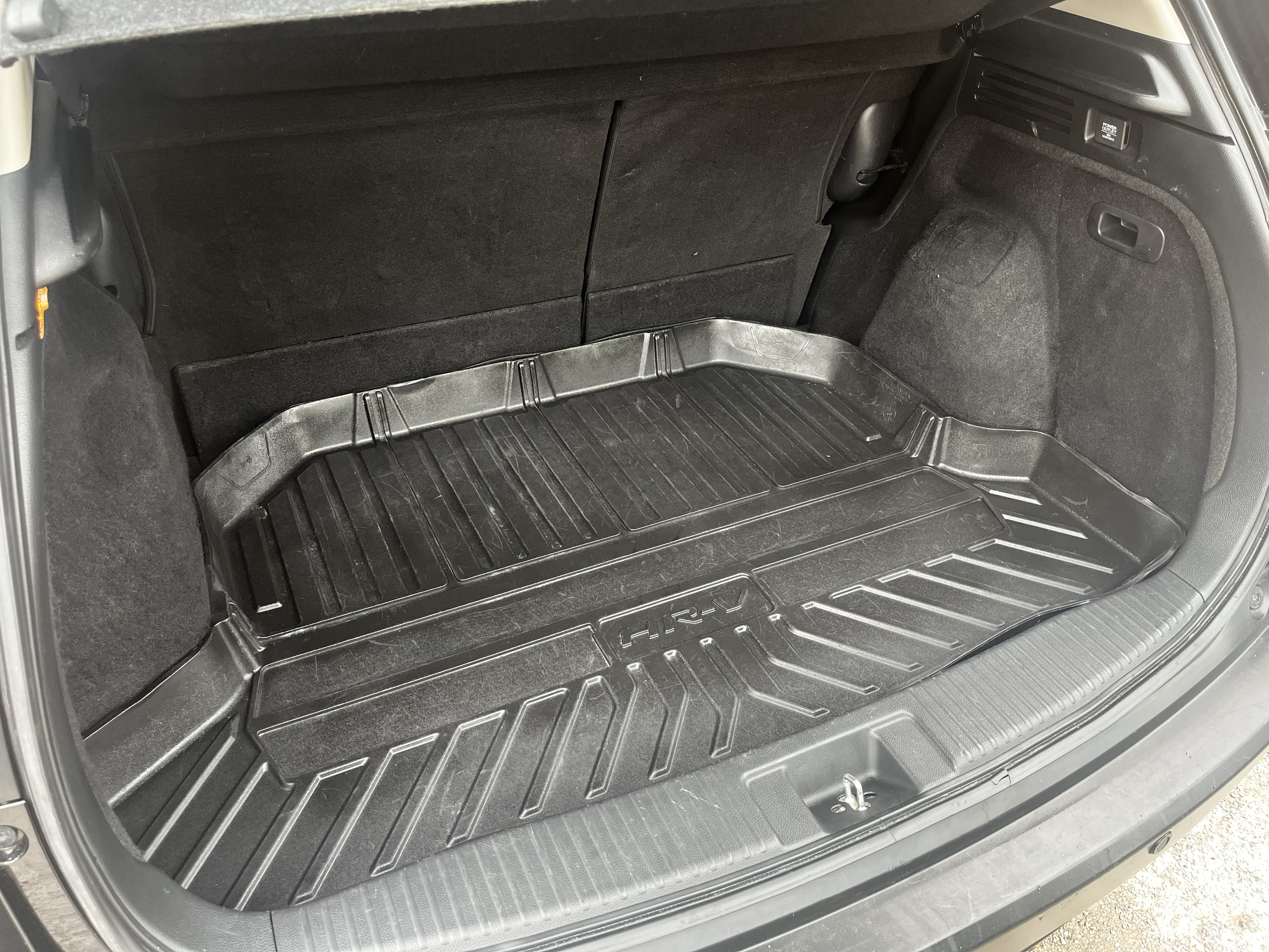 The trunk of a car with a black rubber mat on the floor and folded rear seats visible at the back.