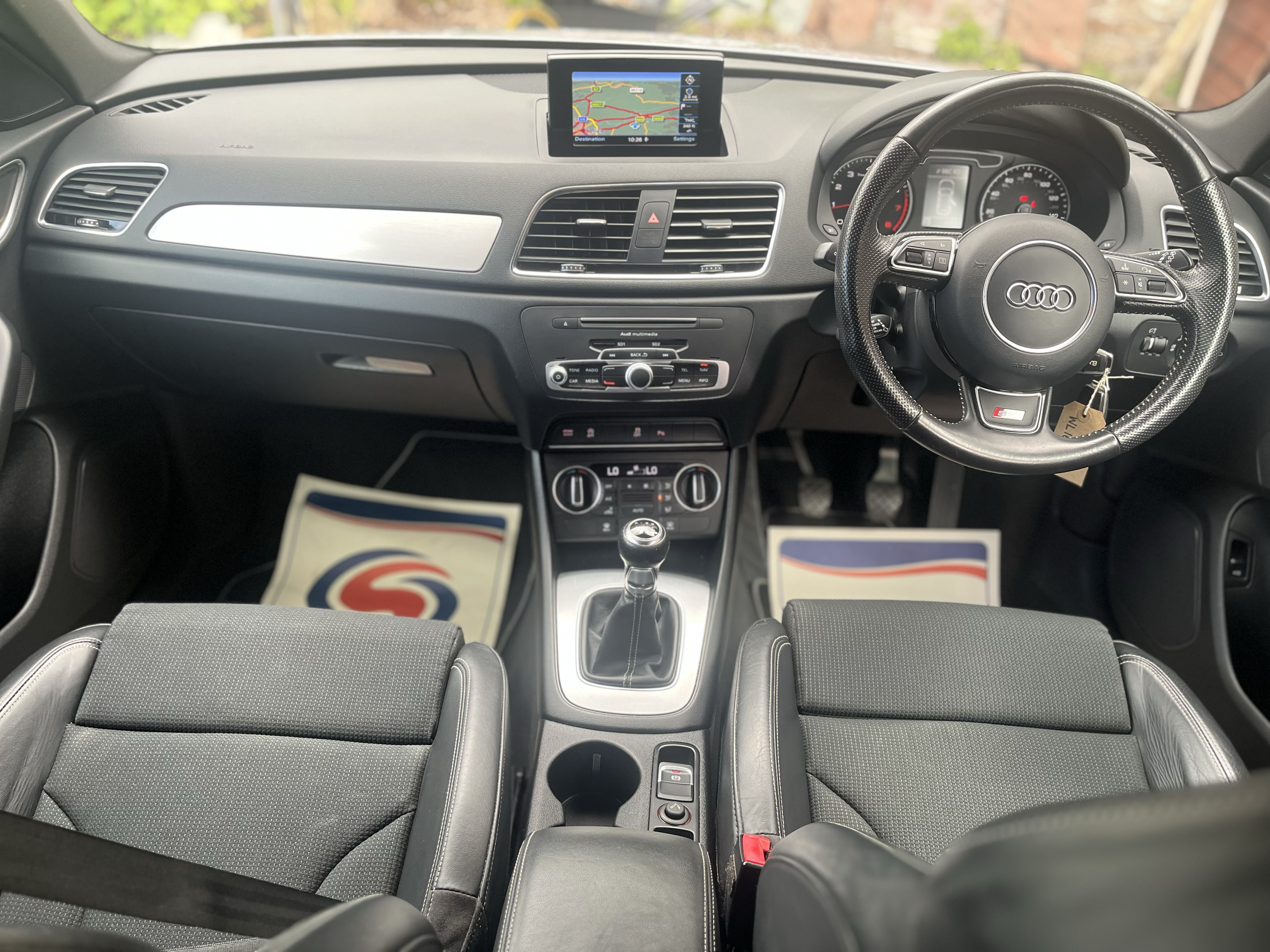 Inside view of an Audi car dashboard and steering wheel with navigation system display.