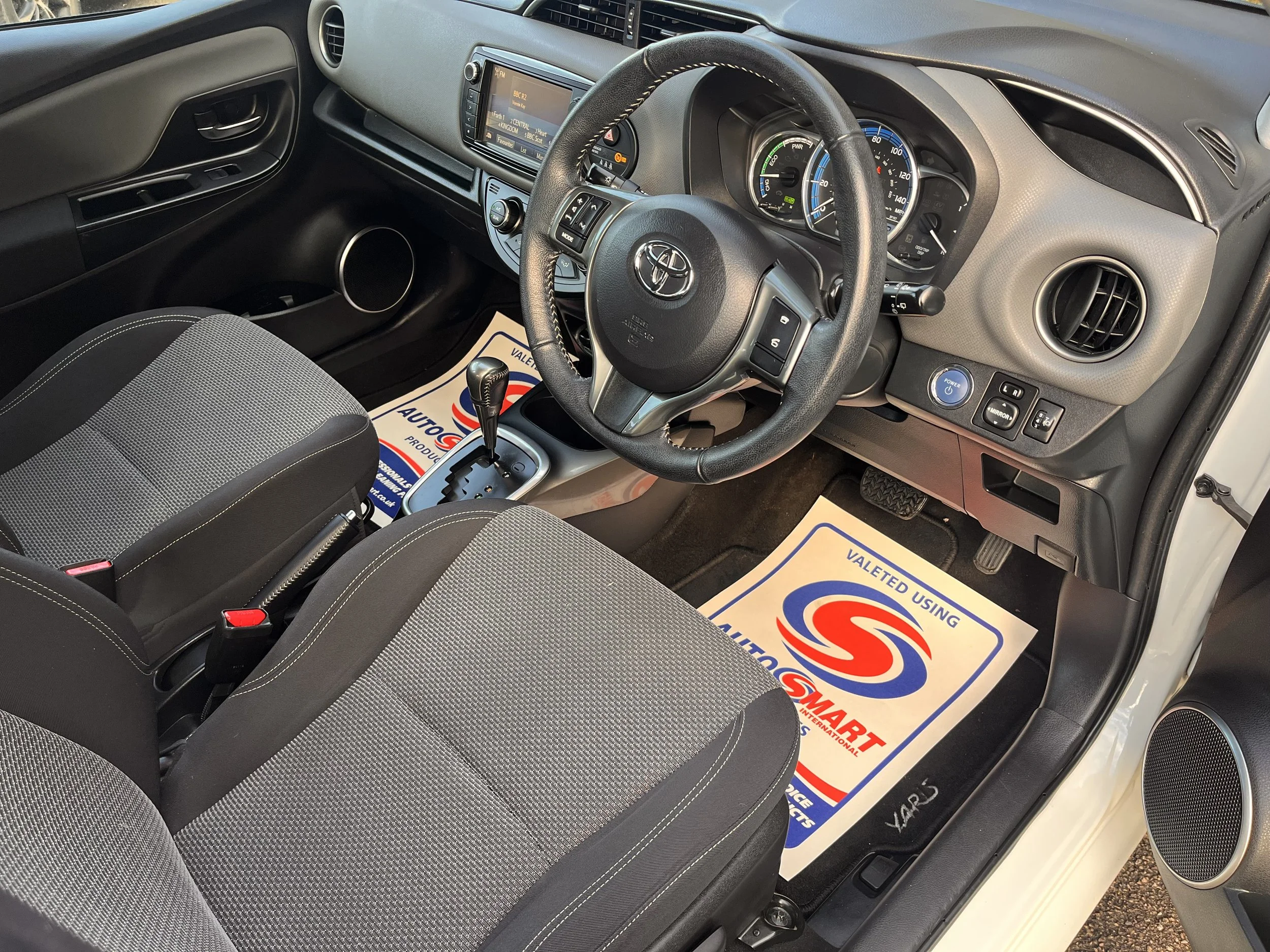 Interior of a Toyota car showing the dashboard, steering wheel, gear shift, front seats, and floor mats with the logo of Valeted using Smart.
