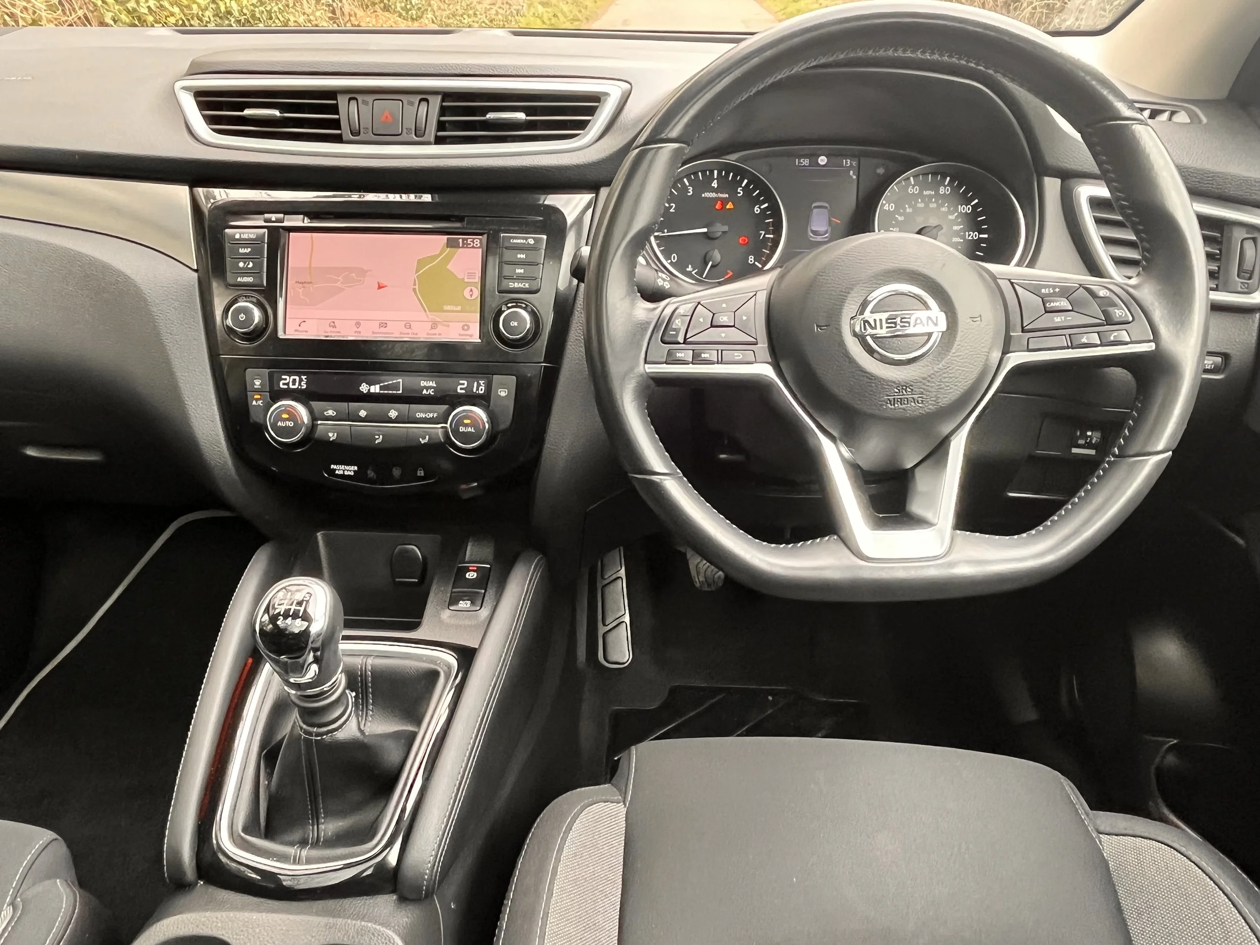 Interior view of a Nissan vehicle dashboard with steering wheel, gear shifter, and infotainment system.