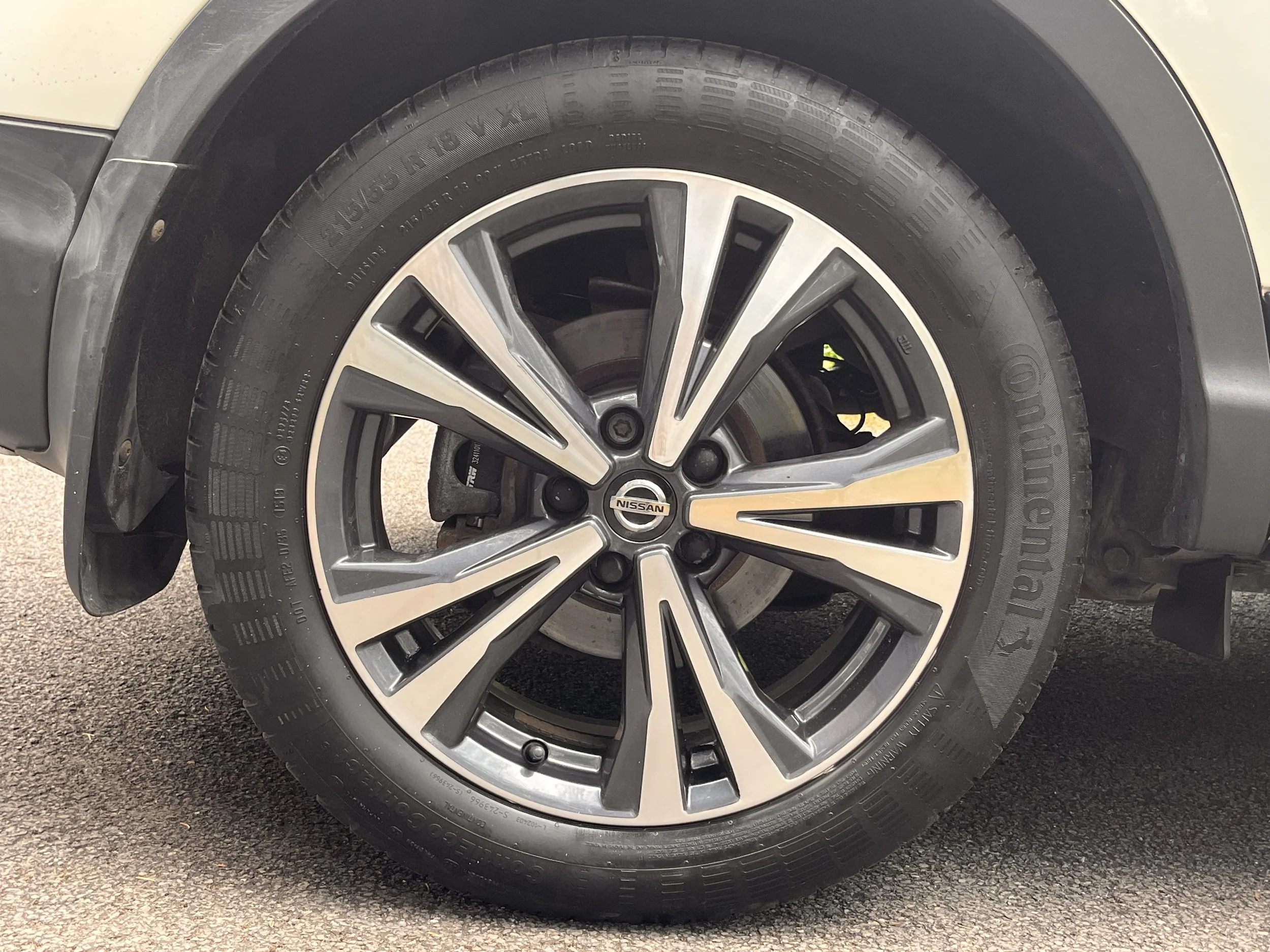 Close-up of a car wheel with a tire branded Continental and an alloy rim with Nissan logo in the center.