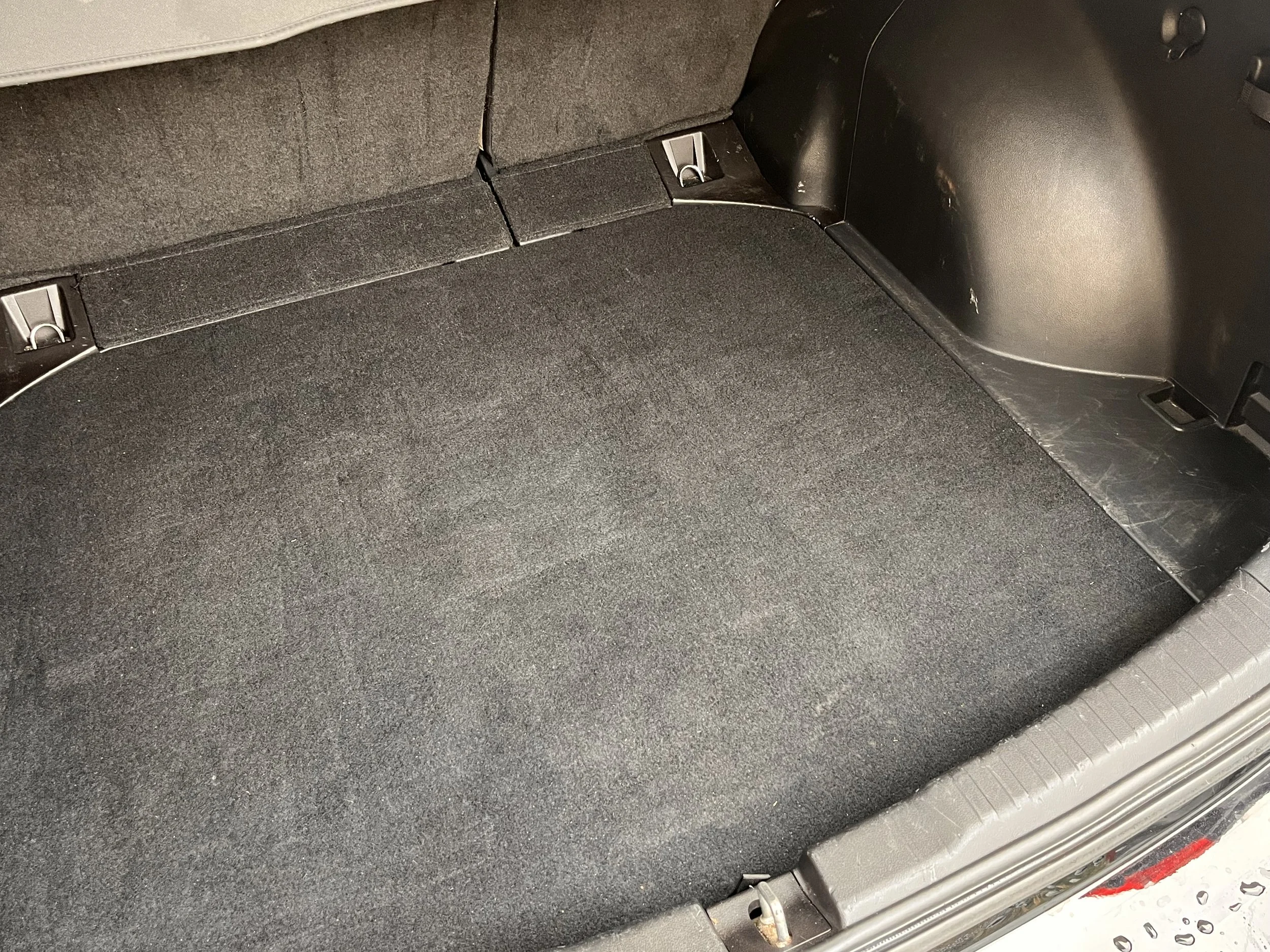 Empty car trunk with black carpeting and side panels