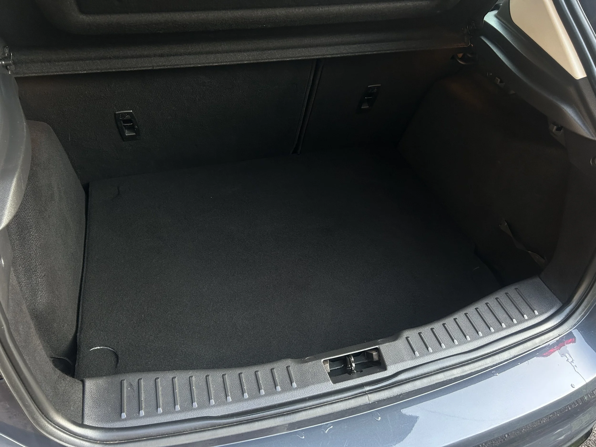 Empty car trunk with black interior and a textured plastic threshold.