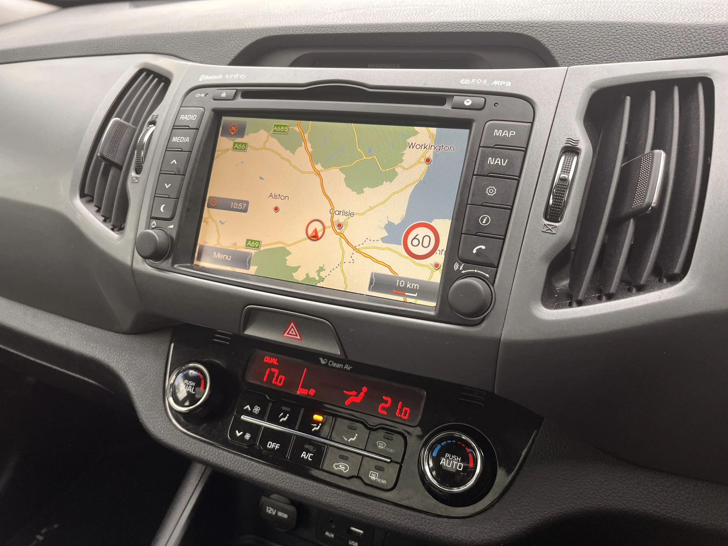 Car dashboard with GPS navigation screen showing a map of the Carlisle area, with traffic, and a speed limit of 60 mph.
