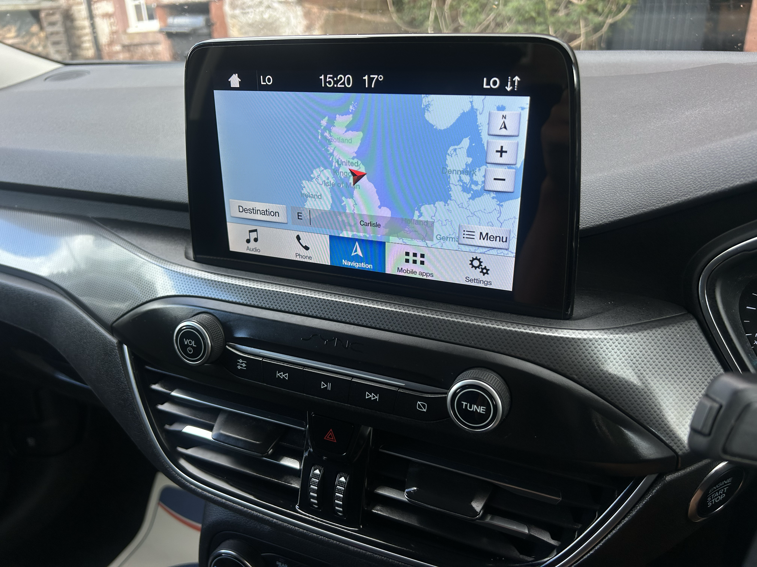 The image shows a car's dashboard with a built-in navigation screen displaying a map of the United Kingdom and surrounding areas, with the time 15:20 and the outside temperature 17°C.