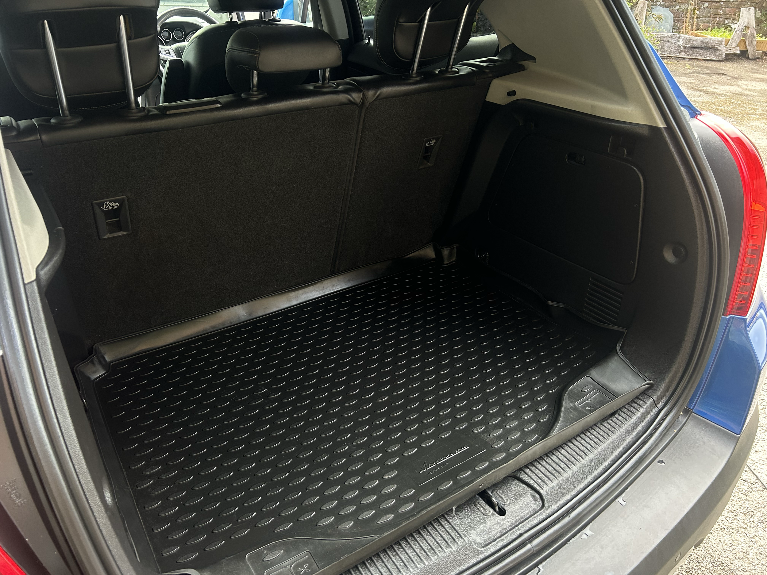 Open trunk of a blue SUV showing a black rubber cargo mat and the back of the rear seats