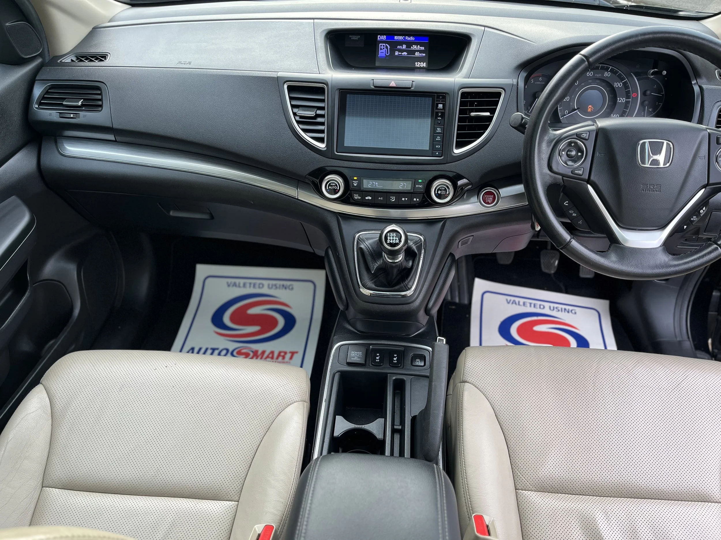 Interior of a Honda vehicle showing the dashboard, steering wheel, gear shift, and front seats with protective floor mats.