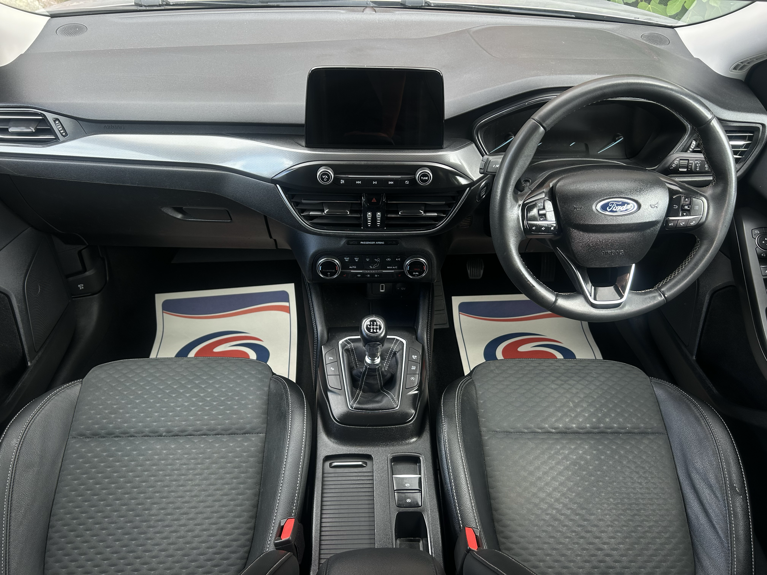 Inside view of a modern Ford car dashboard with steering wheel, center console, and gear shift.