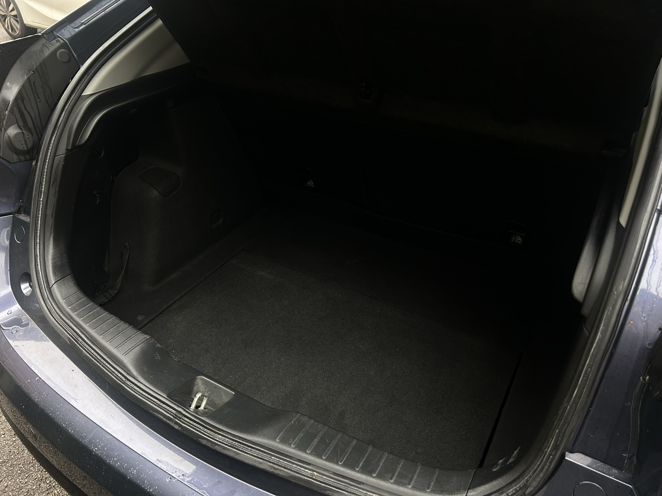 The image shows the open trunk of a vehicle, revealing a clean, empty cargo space with a black interior lining and a protective trim along the edge of the trunk opening.
