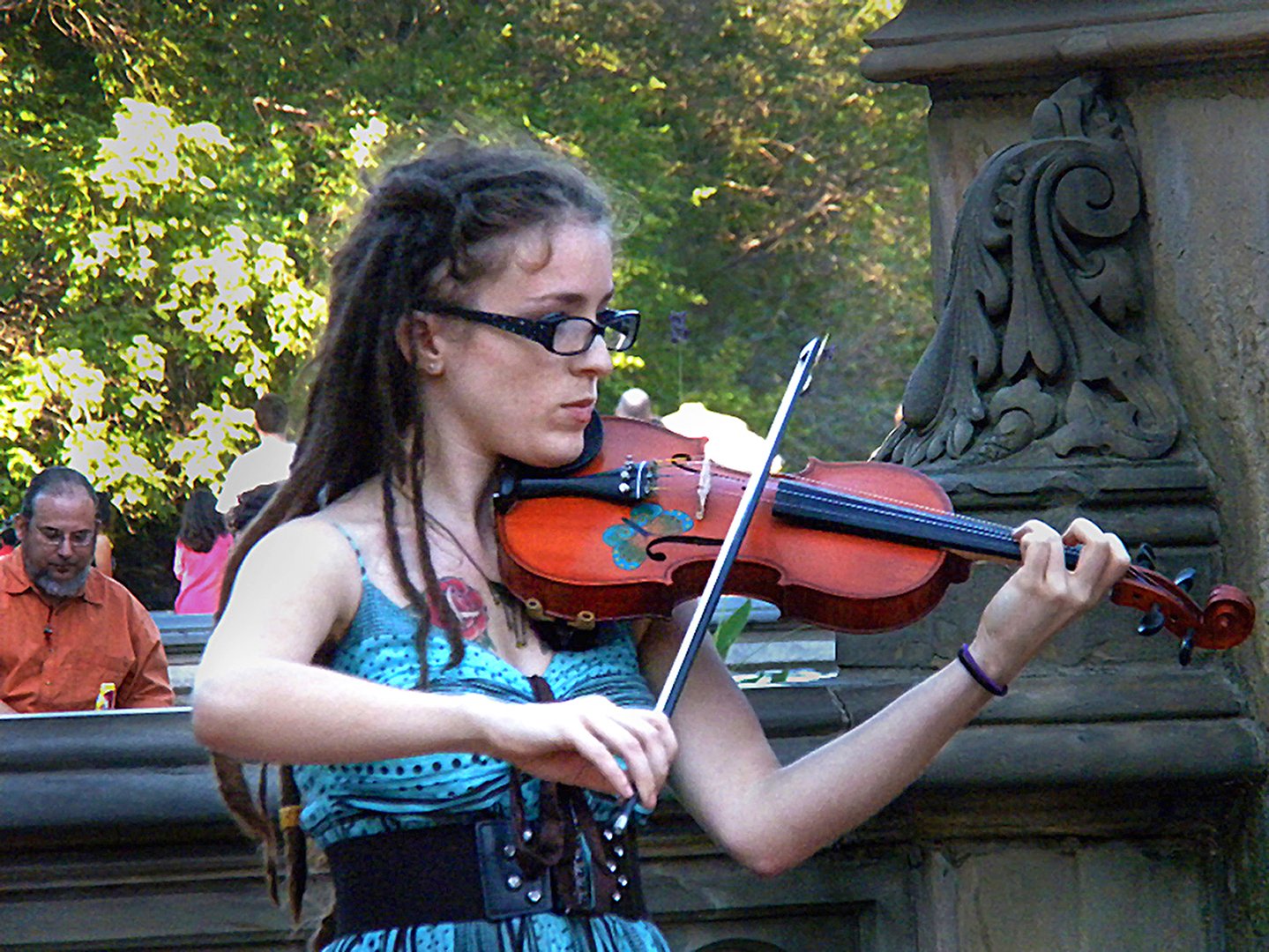 A violinist playing in Central Park, fully absorbed, carrying something private in a public moment — an image of the high achiever who looks most alive precisely when carrying the most.