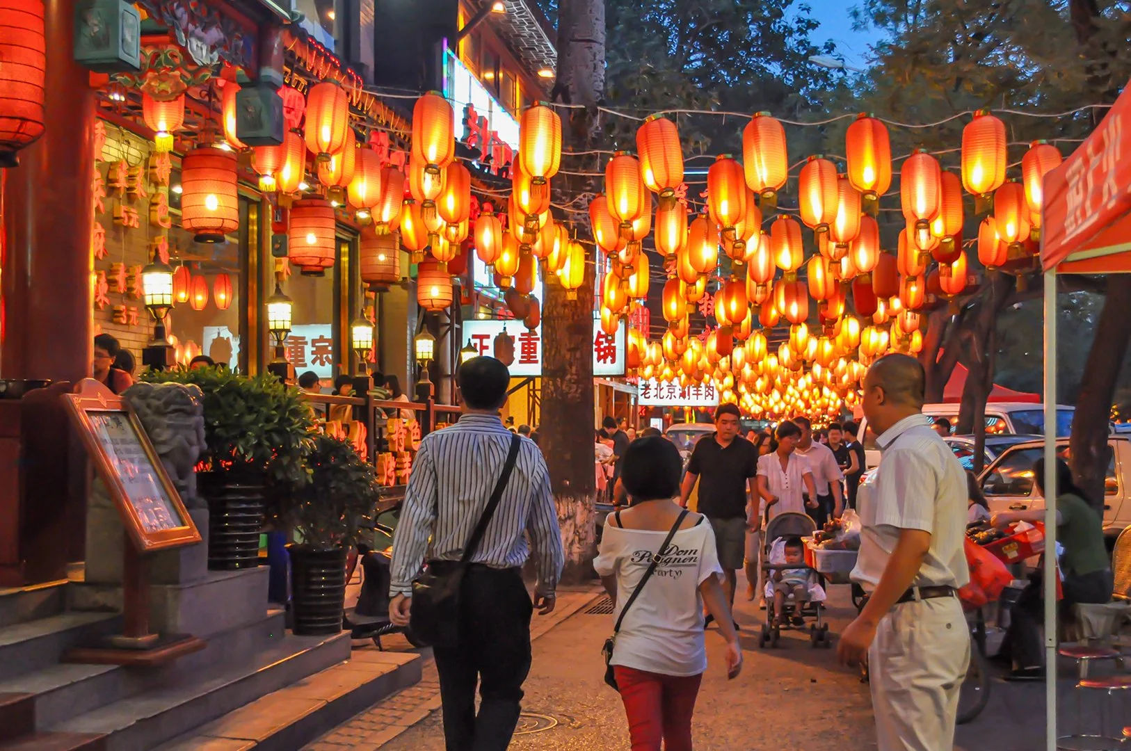Beijing street scene photographed by Dr. Gulshan N. Salim, trauma psychologist in New York. Red lanterns glow above a busy walkway at dusk, symbolizing Haunted House Therapy™ — gentle light guiding trauma recovery, one step at a time.