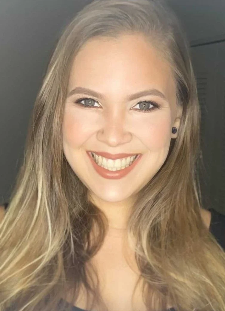 A woman with long blonde hair smiling widely, showing her teeth.