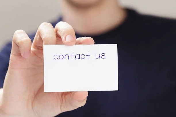 Person holding a card with "contact us" written on it.