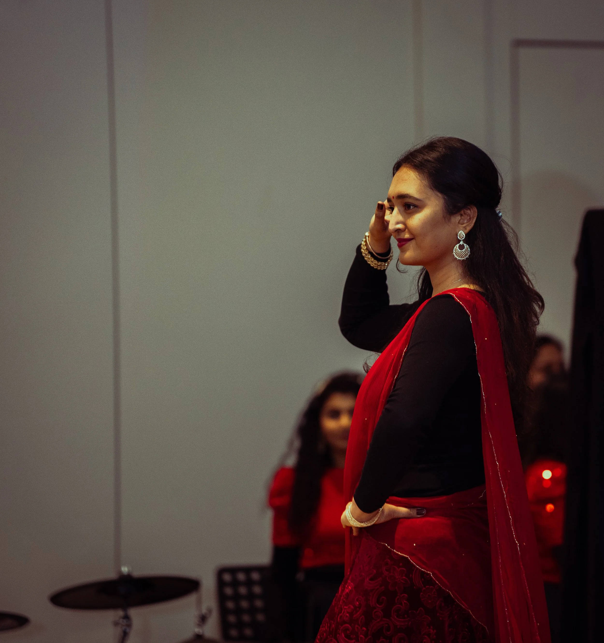 Woman in traditional Indian attire performing a dance move indoors.