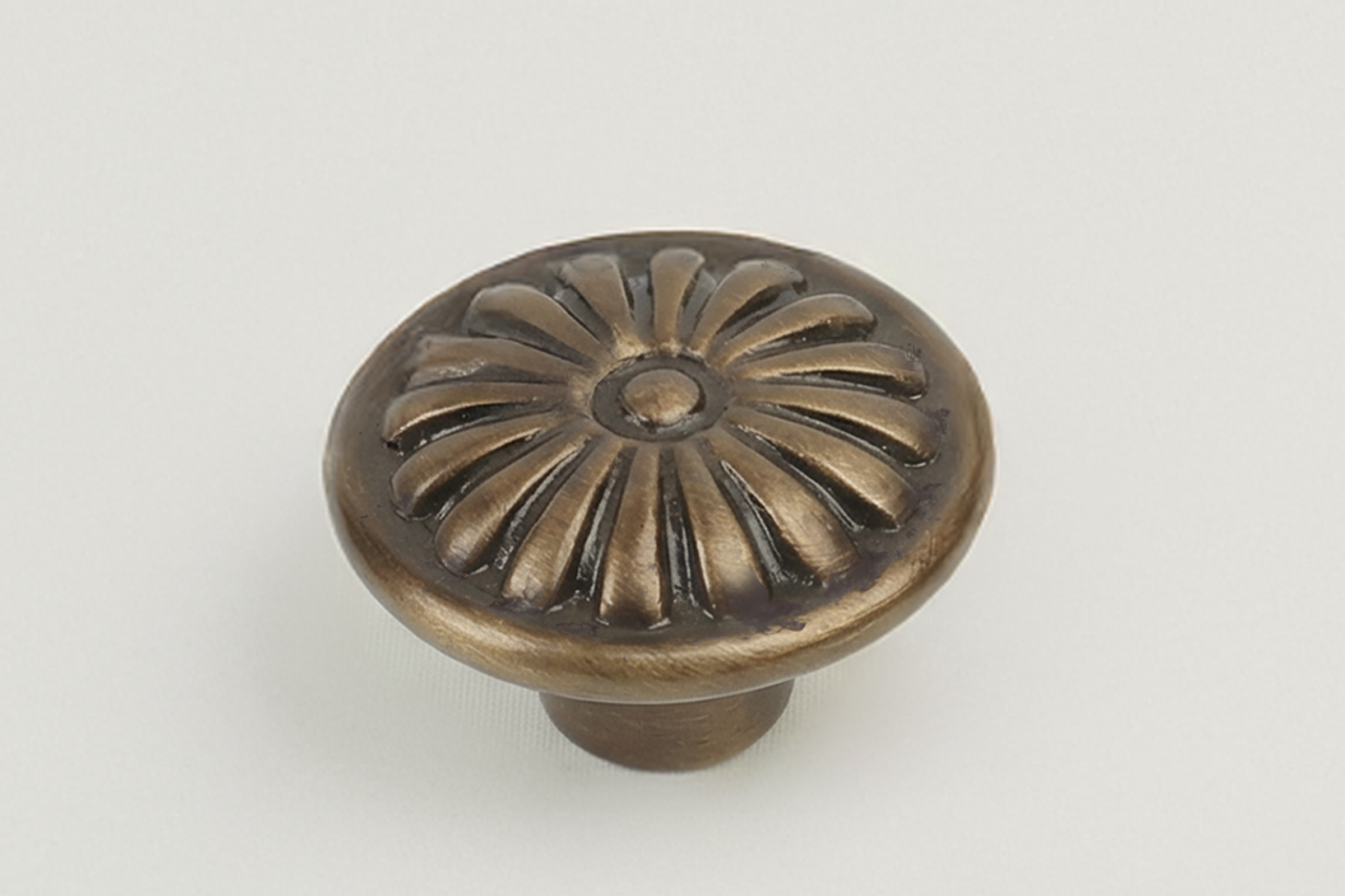 Decorative bronze-colored round knob with a floral sunburst pattern on top, mounted on a white background.