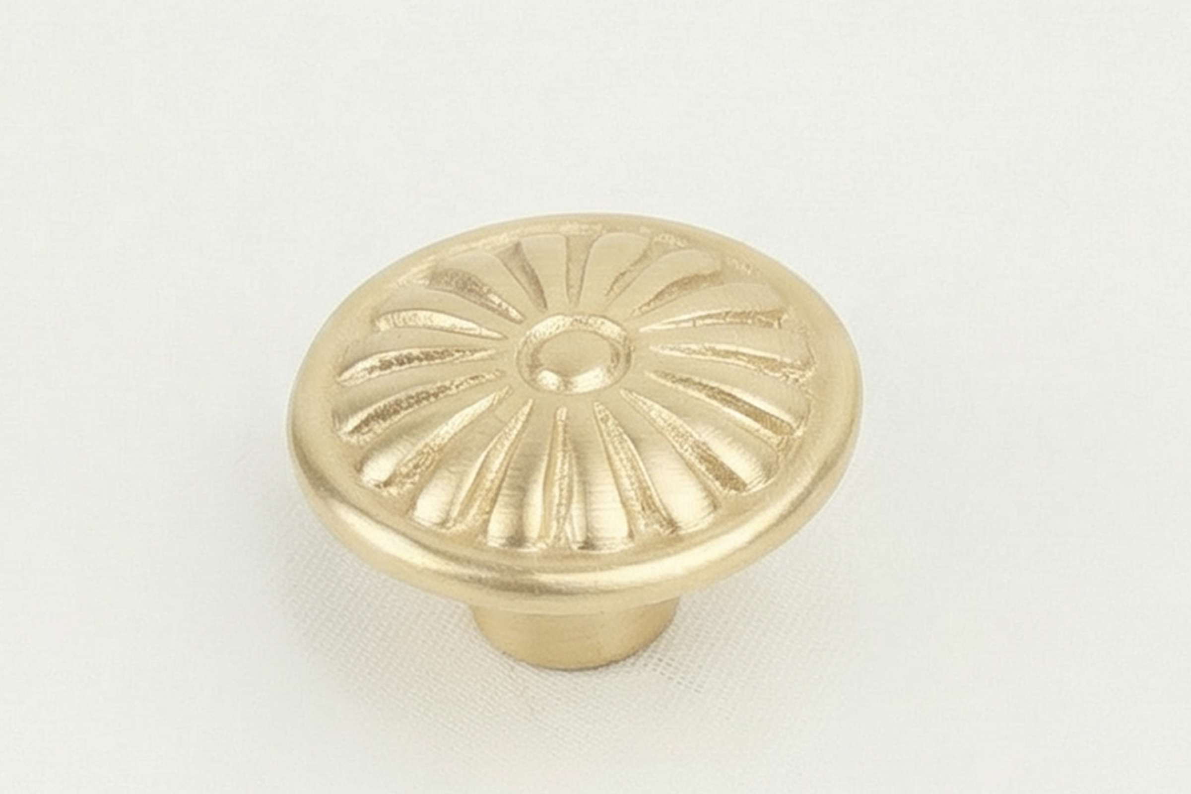 A gold-colored metallic drain cover with a circular pattern of radial slits, photographed against a white background.