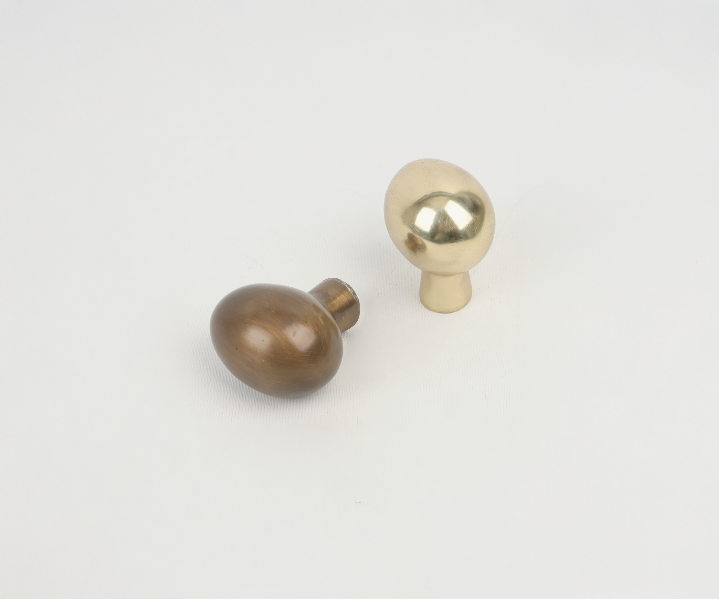 Two metallic mushroom-shaped objects, one gold and one bronze, placed on a white background.