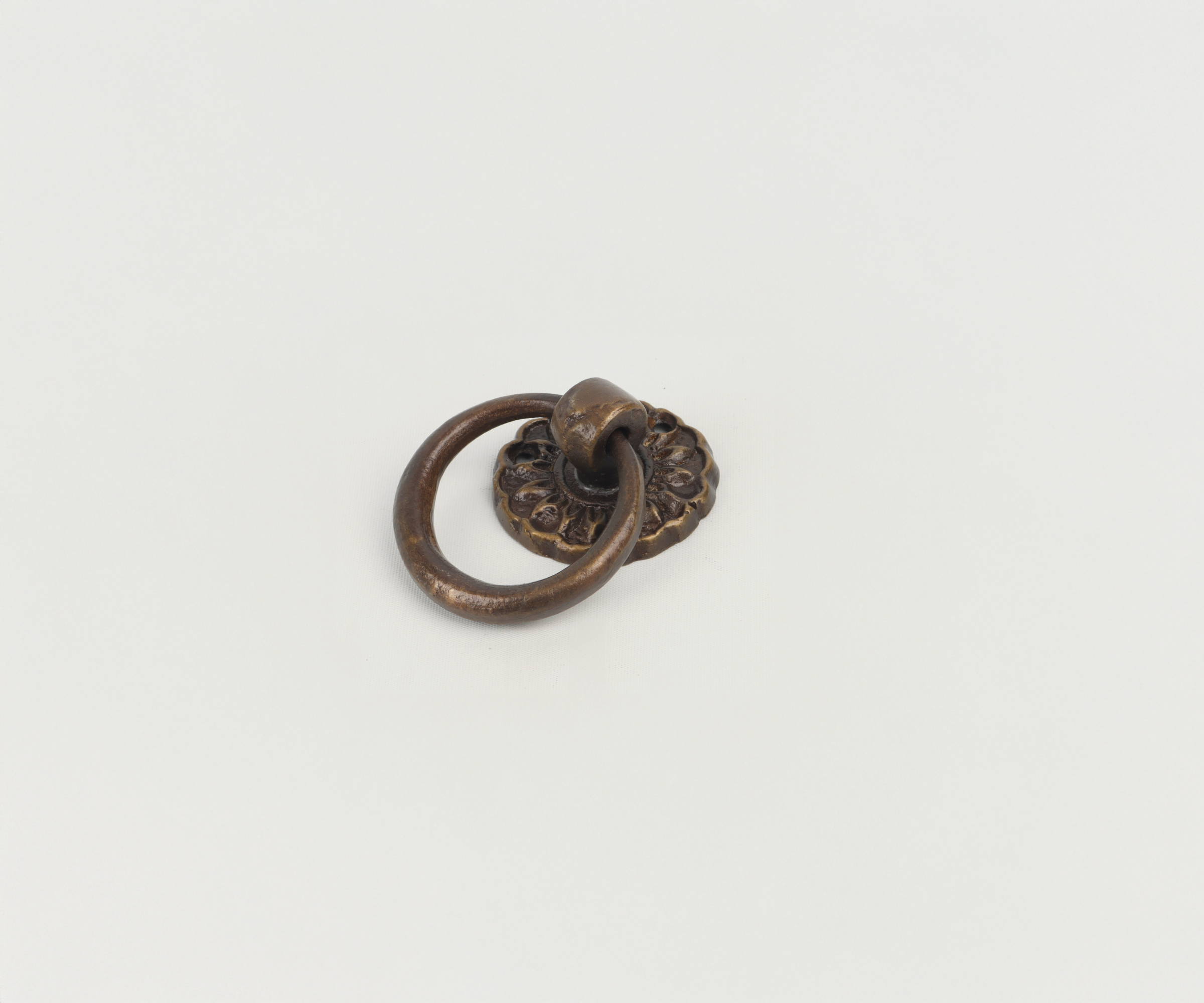 Close-up of an antique bronze door knocker with a floral design on a white background.