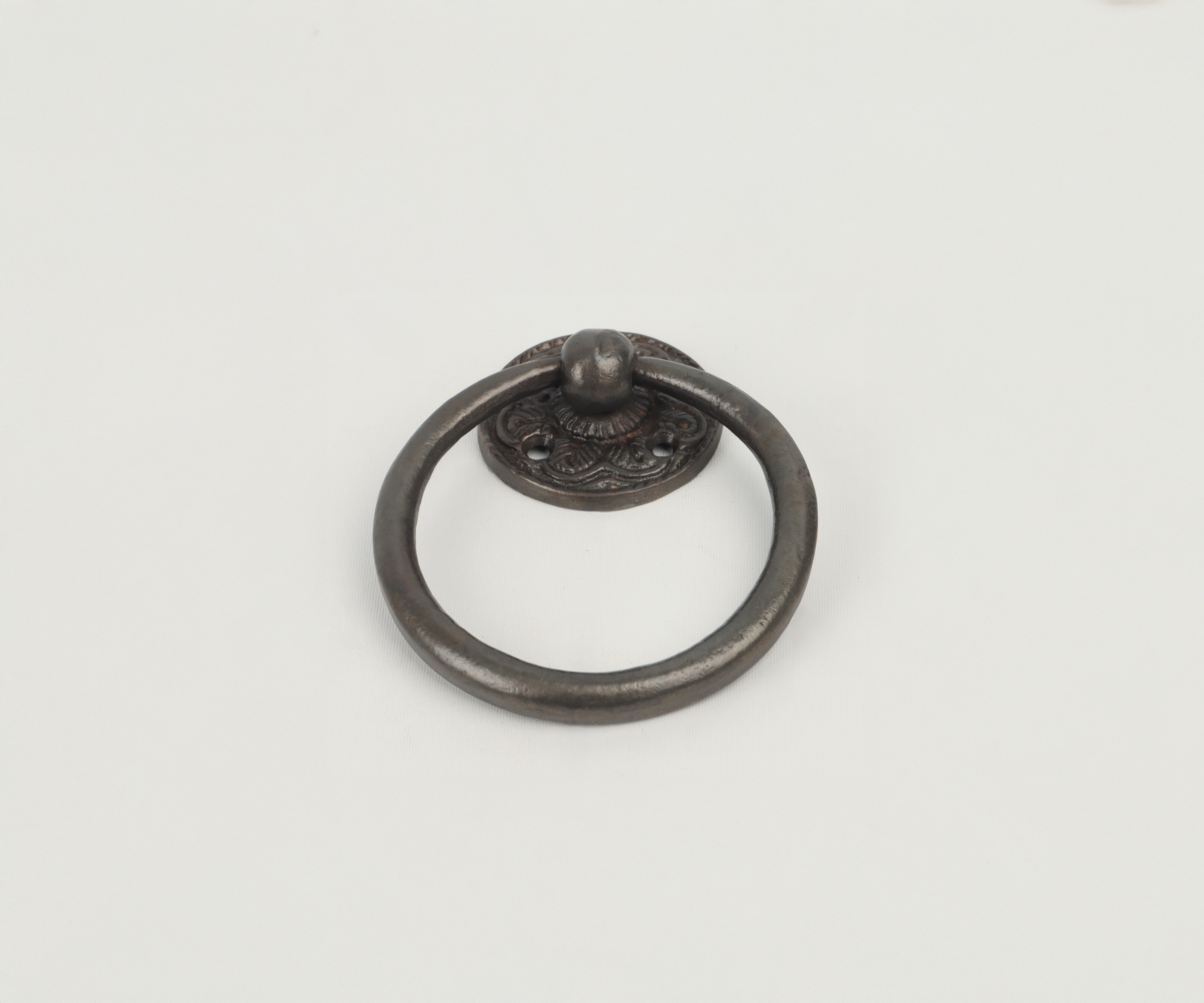 A decorative metal door knocker with a circular handle and ornate base plate on a plain white background.