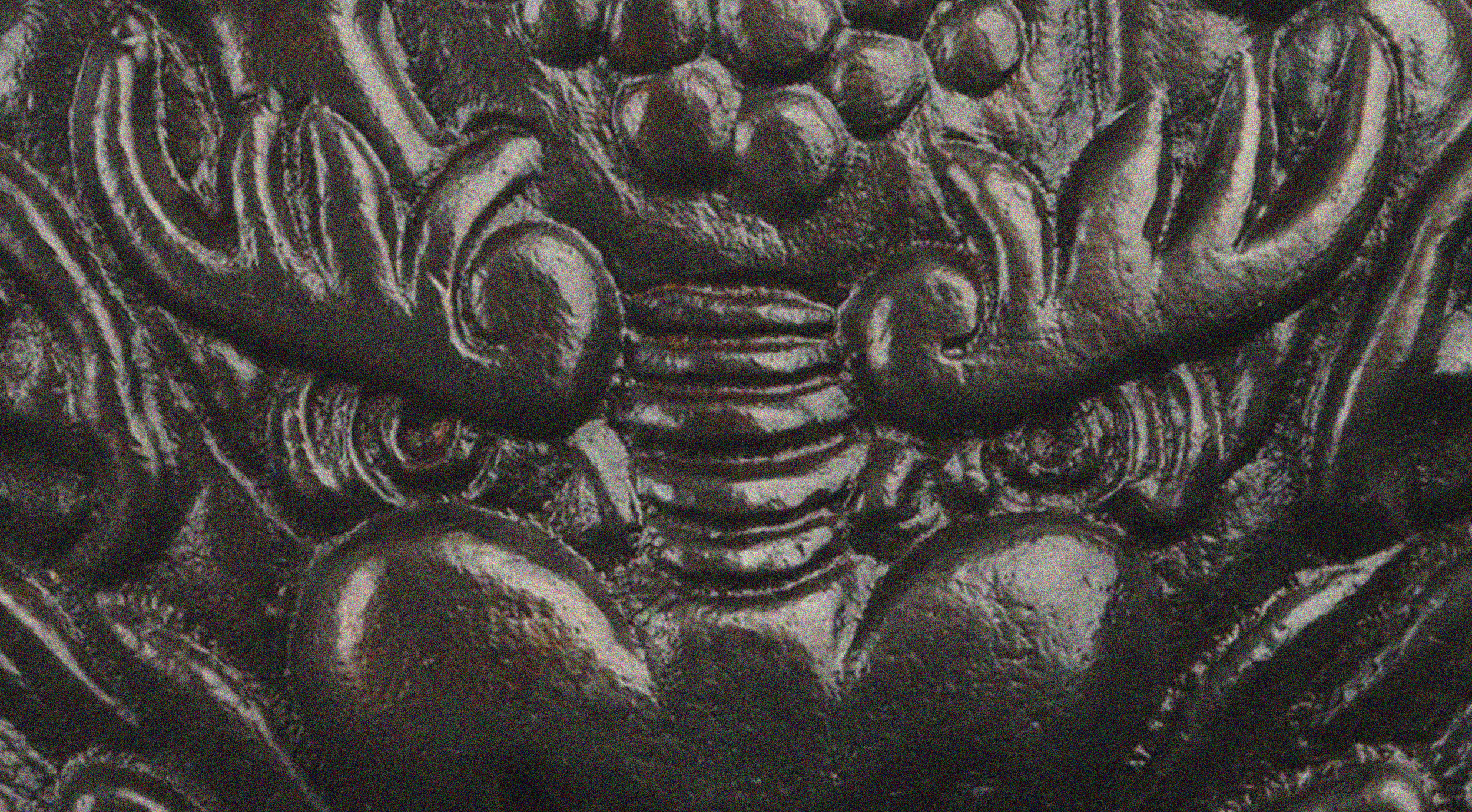 Close-up of an ornately carved black stone sculpture with intricate swirling patterns and layered textures.