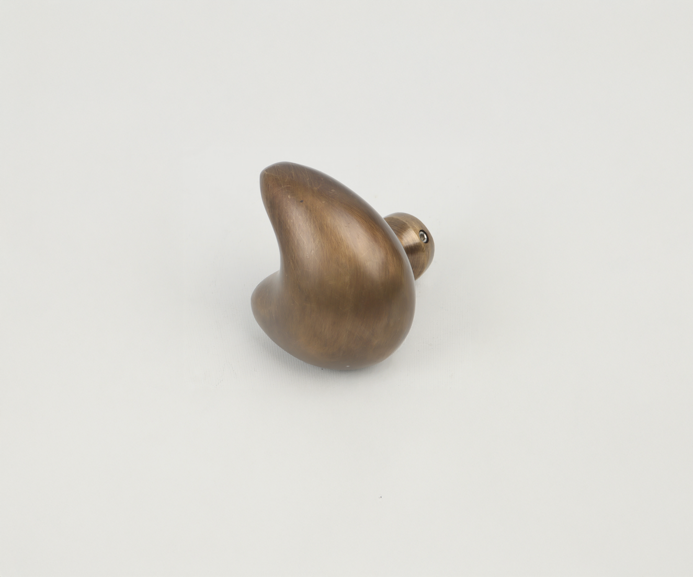 A brown, wooden, decorative whale figurine placed on a plain white surface.