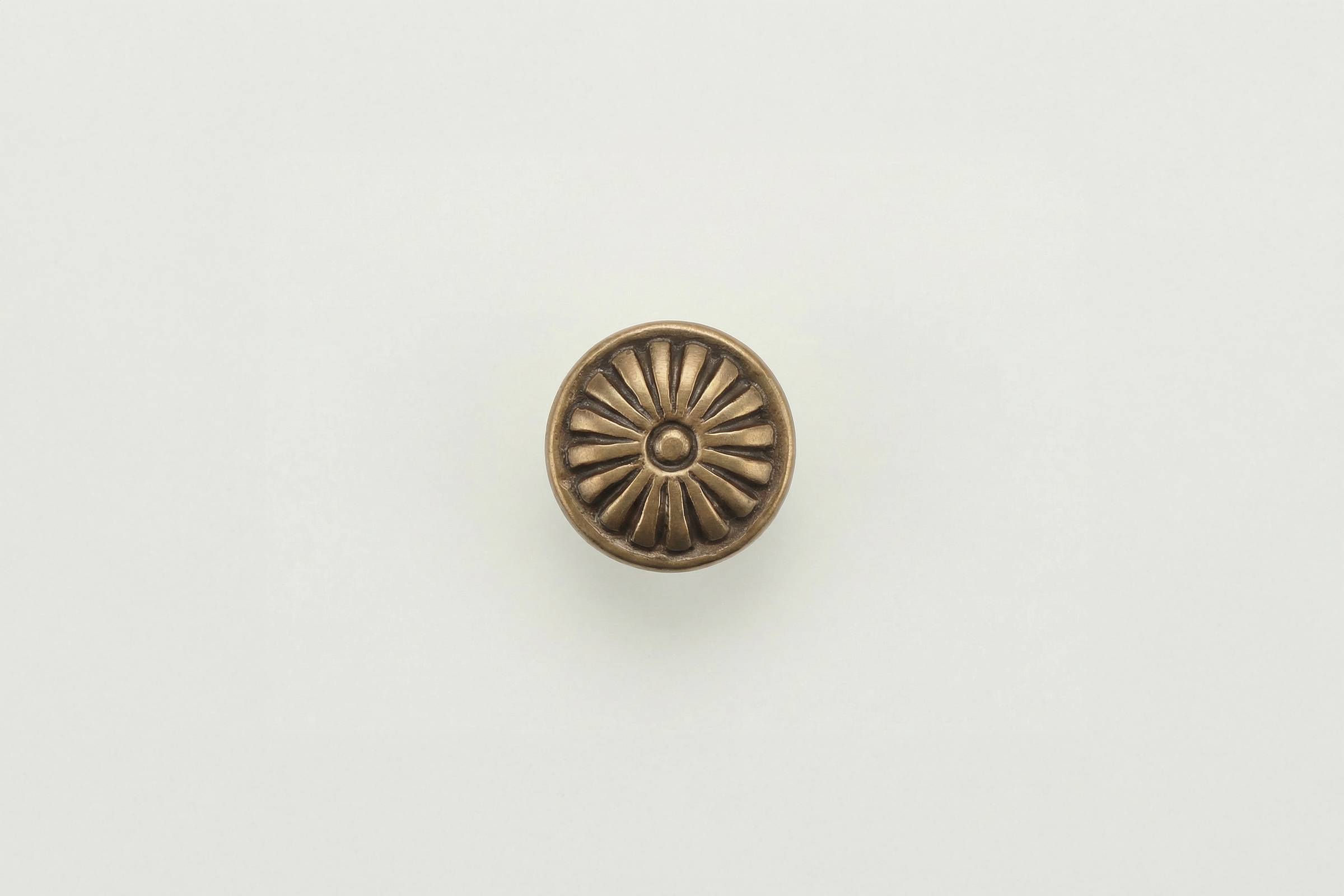 Top view of a decorative round bronze door handle on a plain white door.