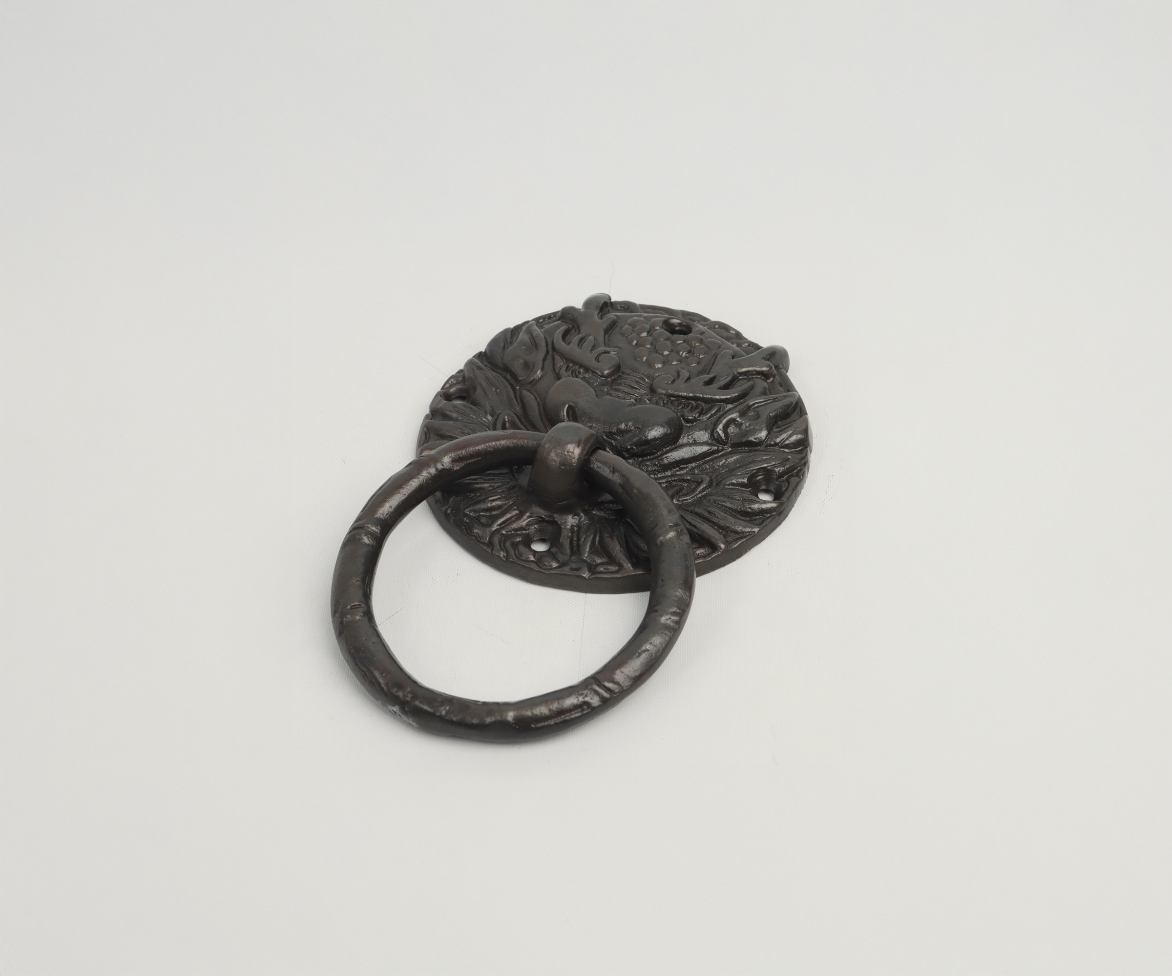 Close-up of a vintage iron door knocker with dragon and floral designs on a plain white background.