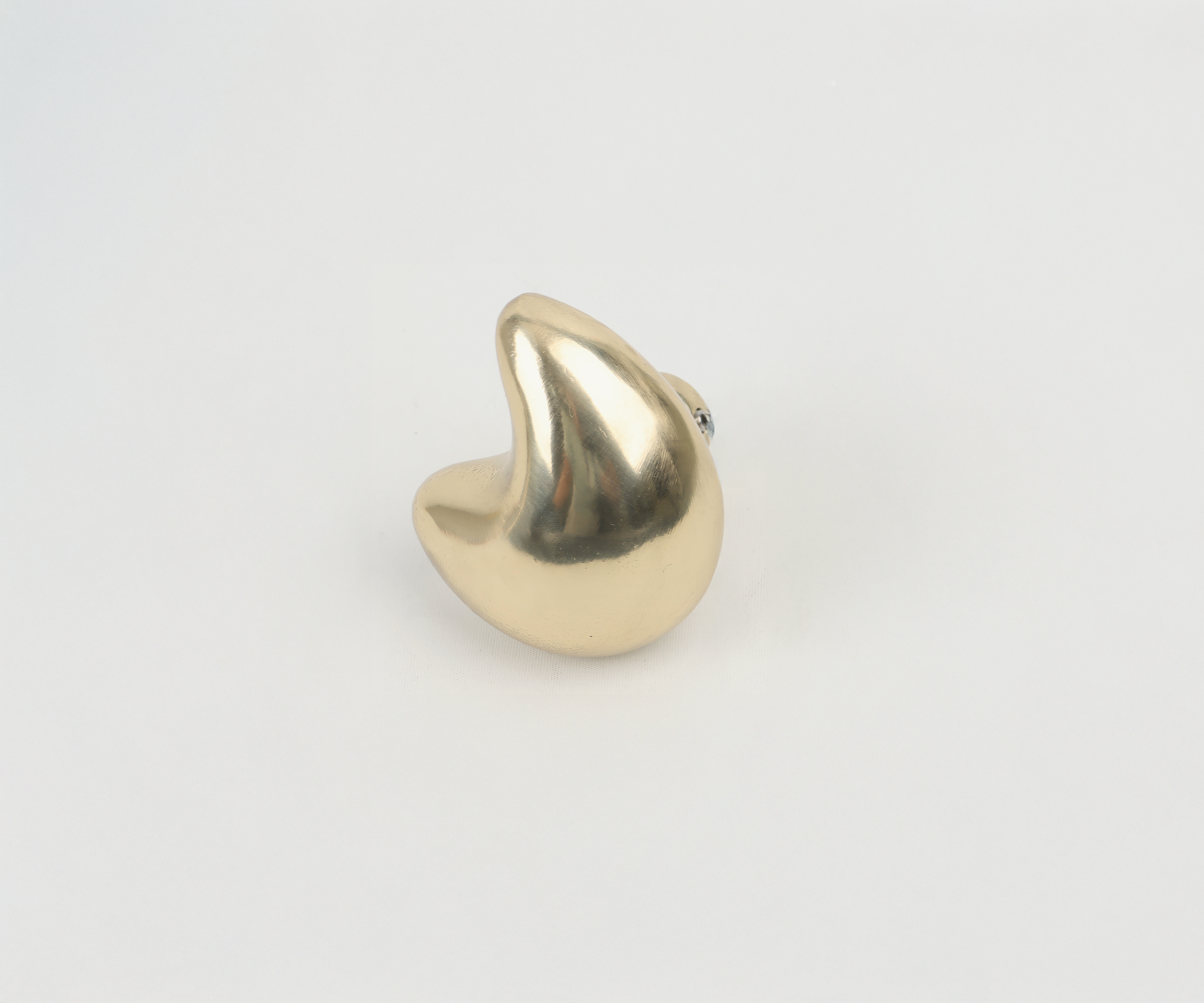 A gold-colored, heart-shaped object with a shiny, reflective surface on a white background.