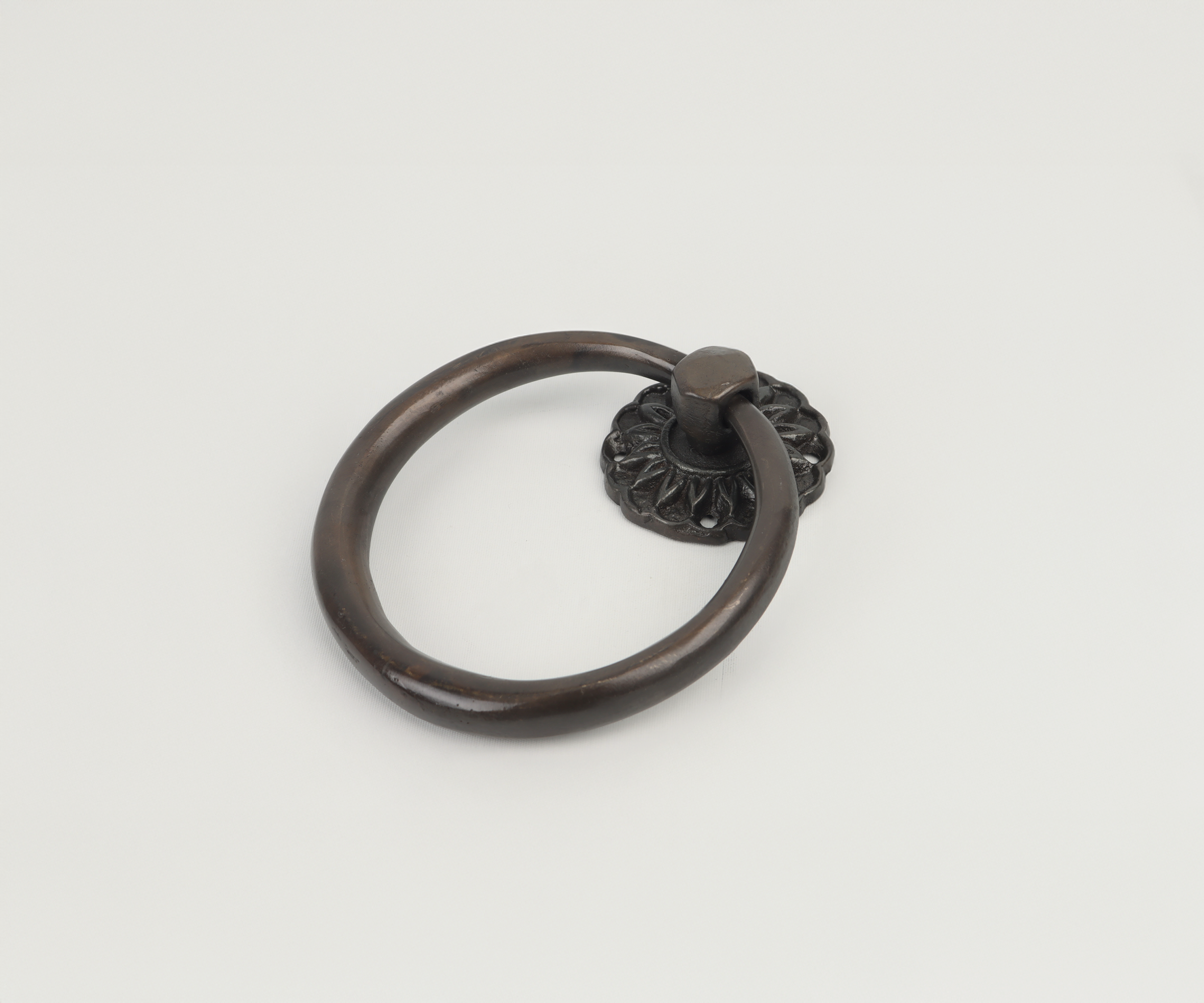 A circular antique black door knocker with a decorative base, placed on a plain white background.