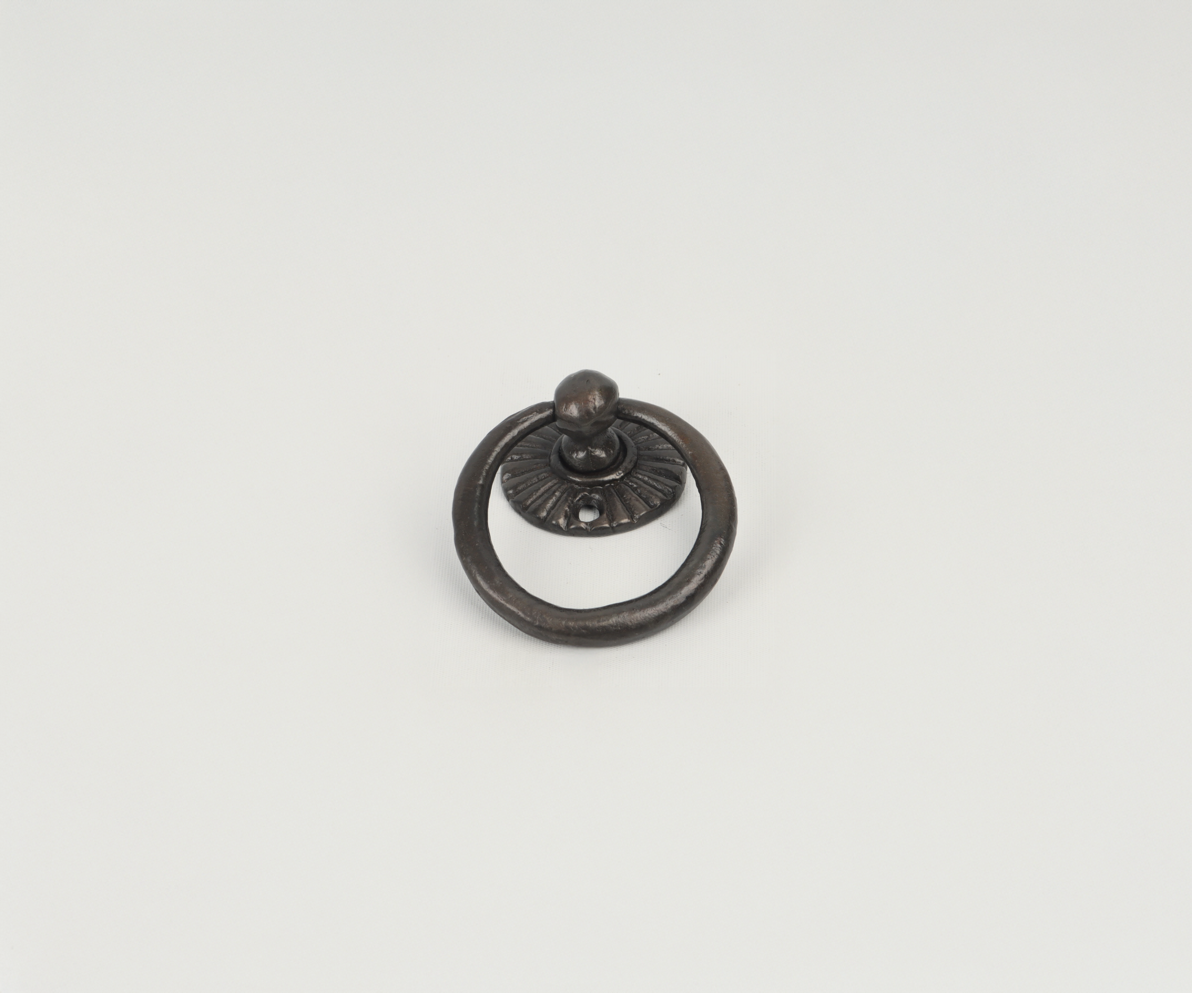 A vintage metal drawer pull with a circular ring and decorative base, mounted on a plain white background.