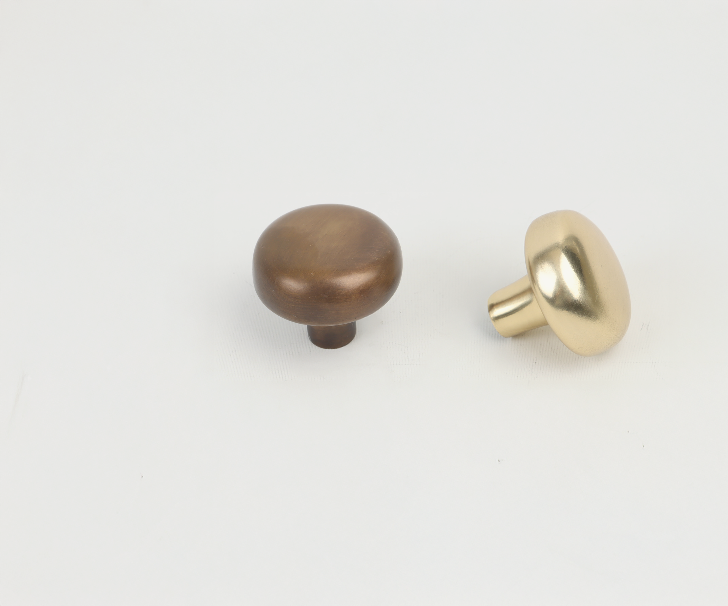 Two door knobs on a plain white background, one brown and the other gold.