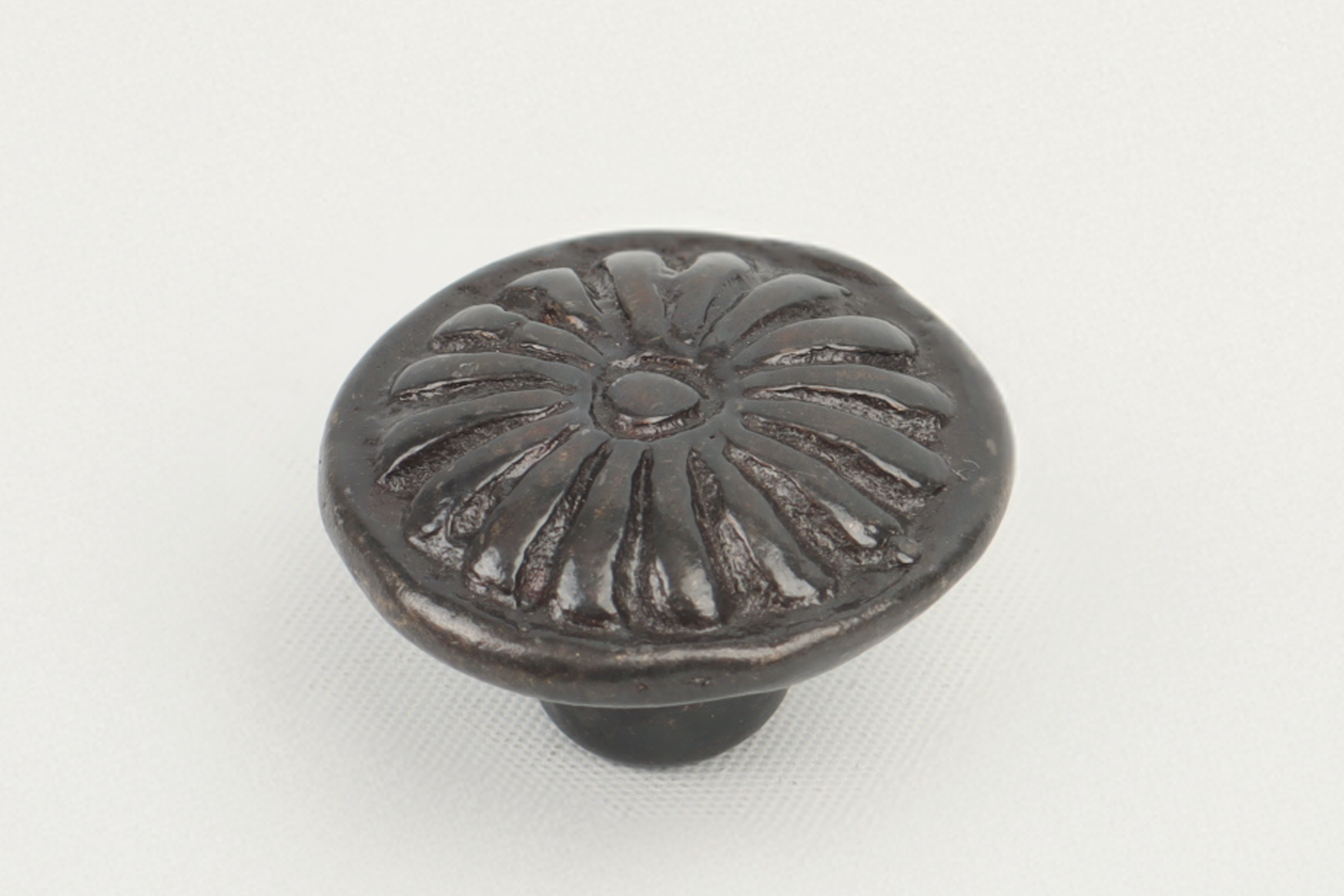 Dark metallic antique drawer knob with floral pattern, round shape, and raised design, on a white background.