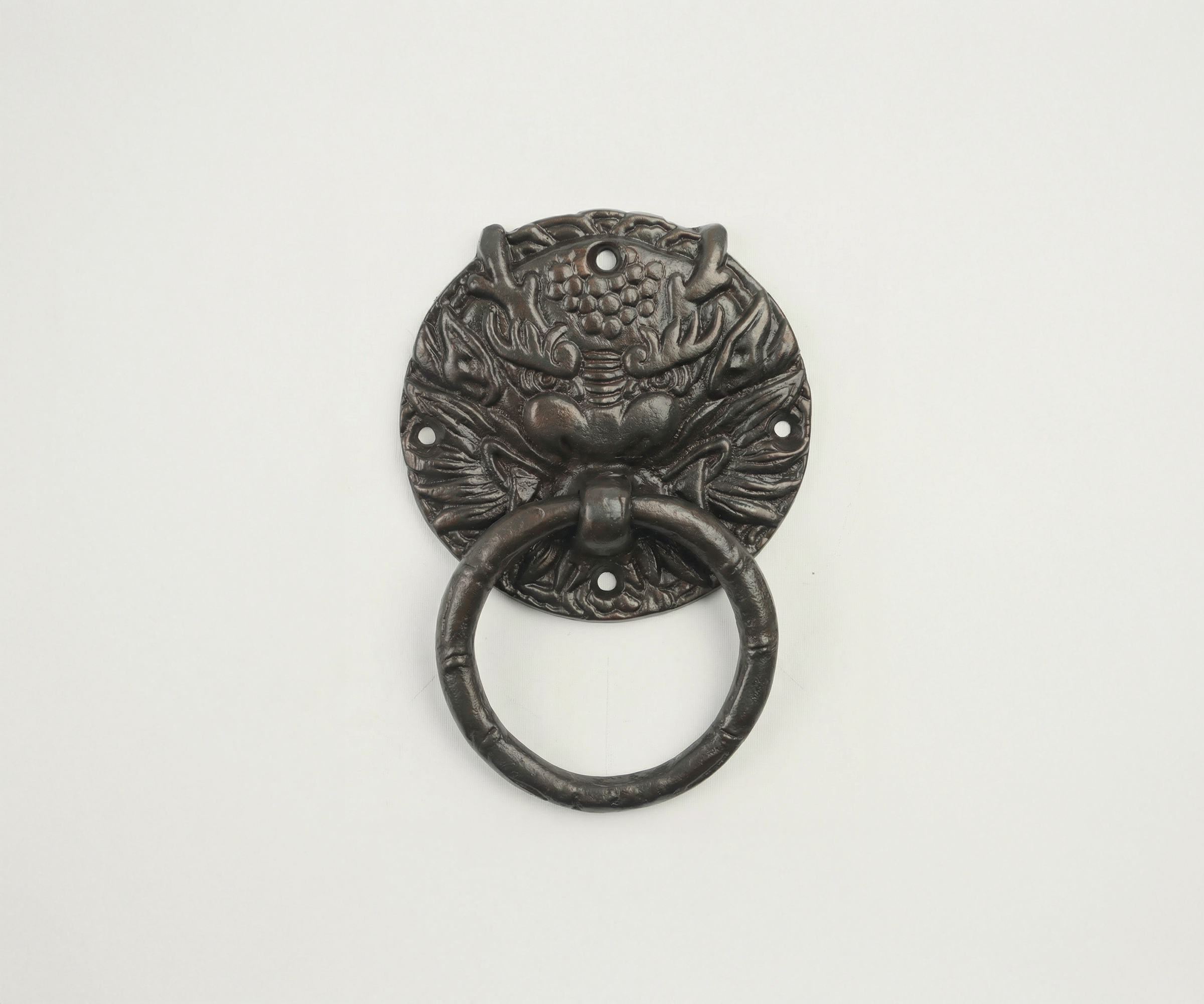 Decorative metal door knocker shaped like a fierce animal face, with a ring in the mouth, mounted on a white background.