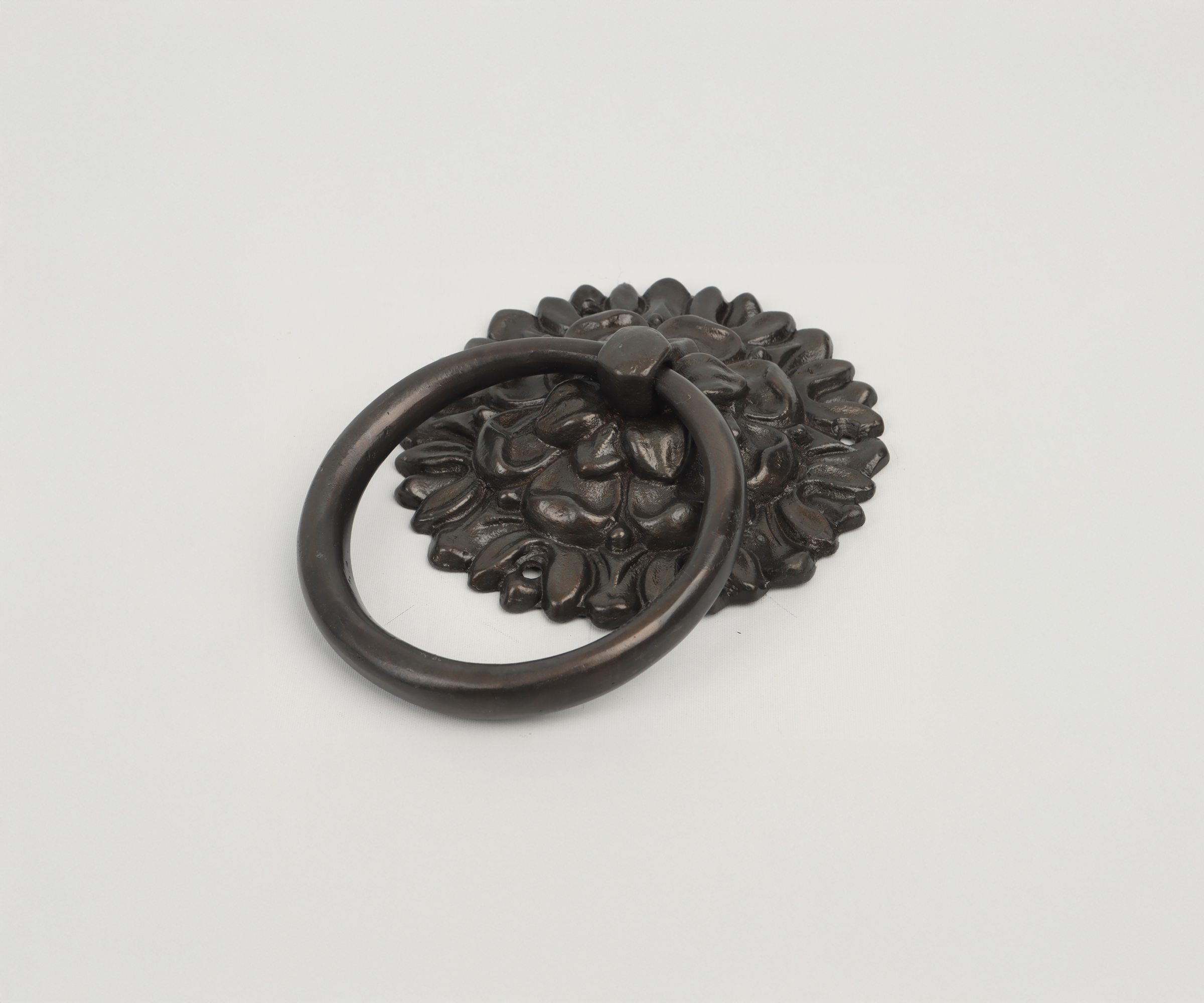 Decorative metal door knocker with a floral design and a circular handle.