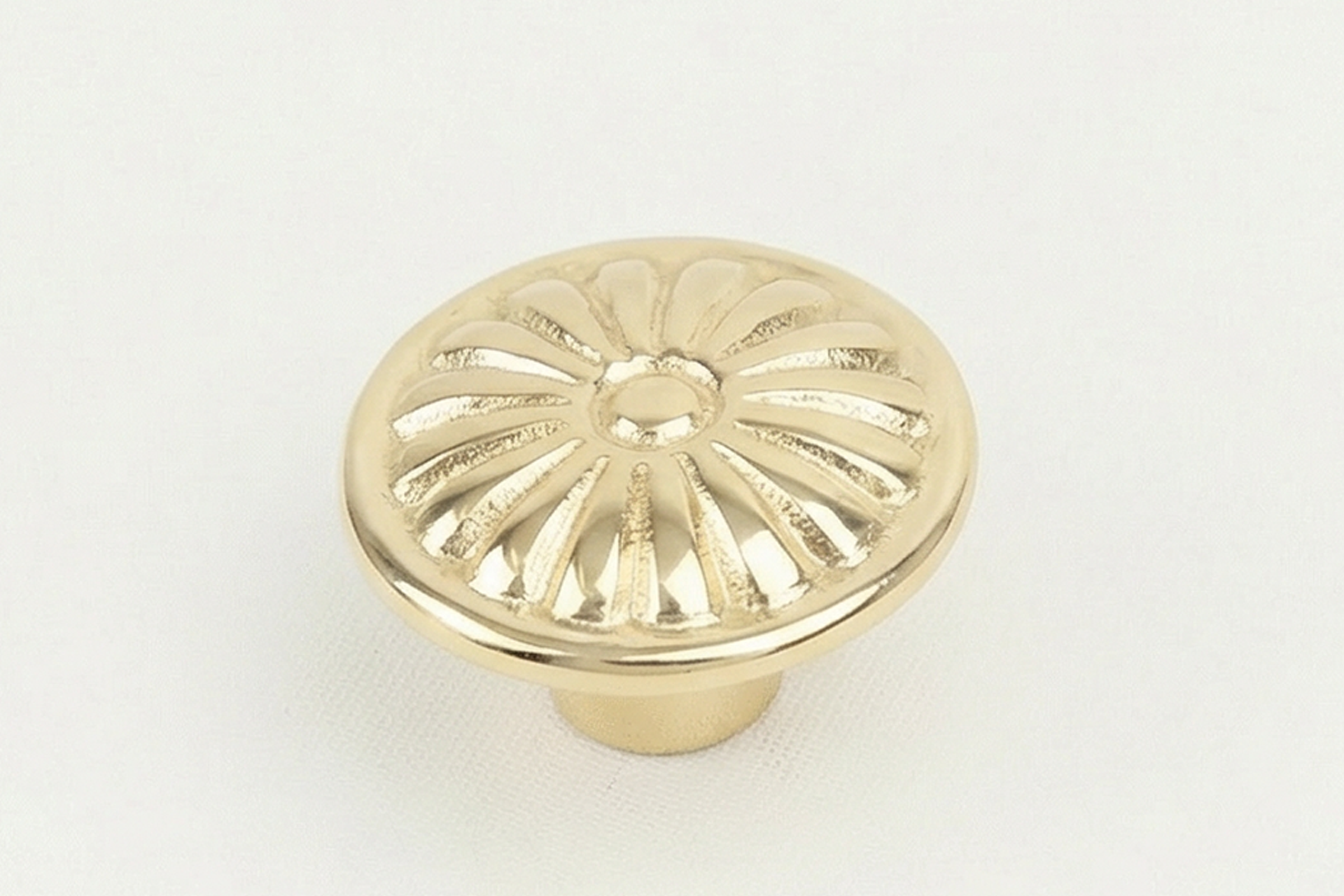 Gold-colored decorative item with a central hole and radial lines, resembling a small ornamental grate or cover against a plain white background.