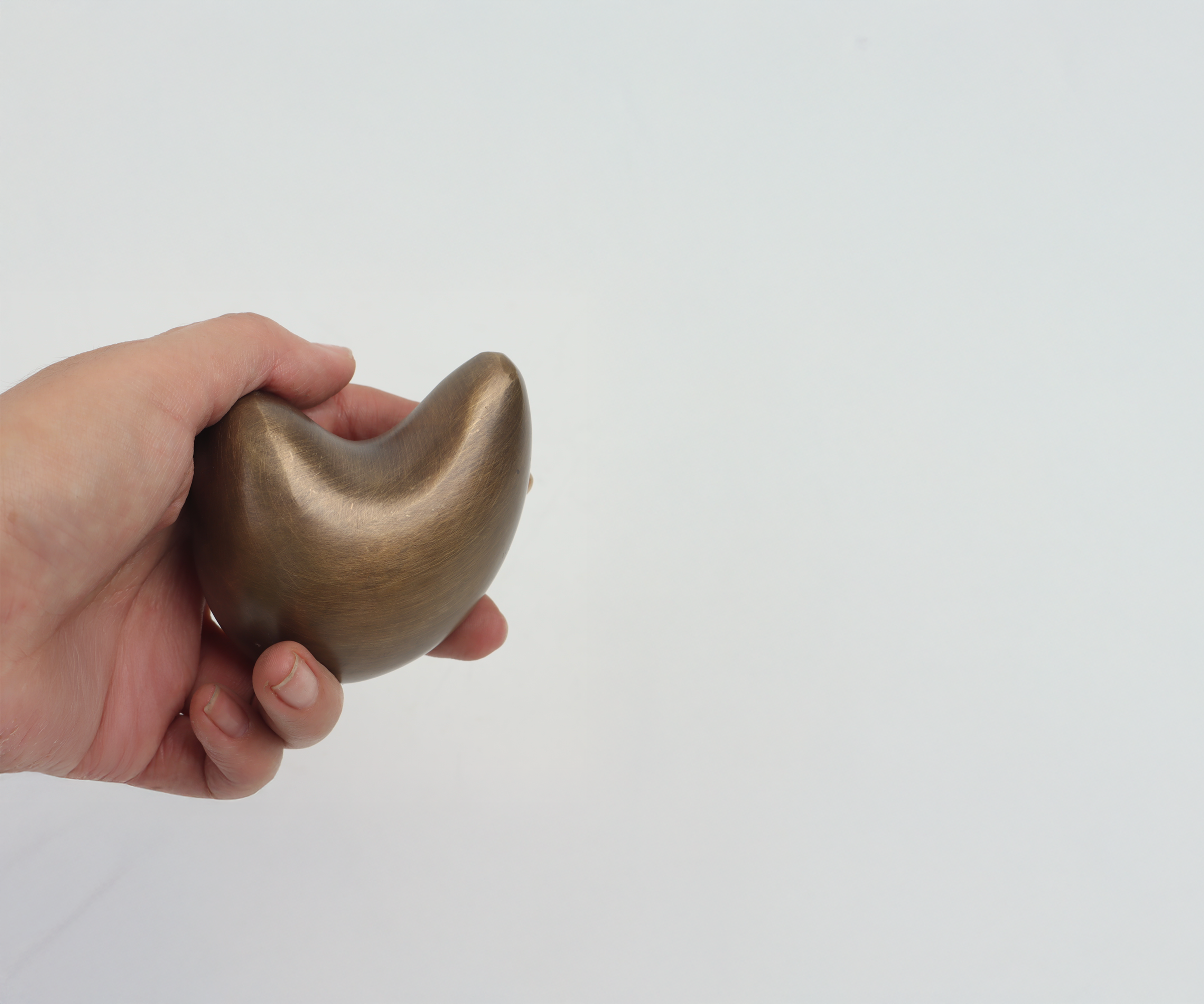 A person's hand holding a smooth, rounded, wooden object resembling the shape of a bean against a plain white background.