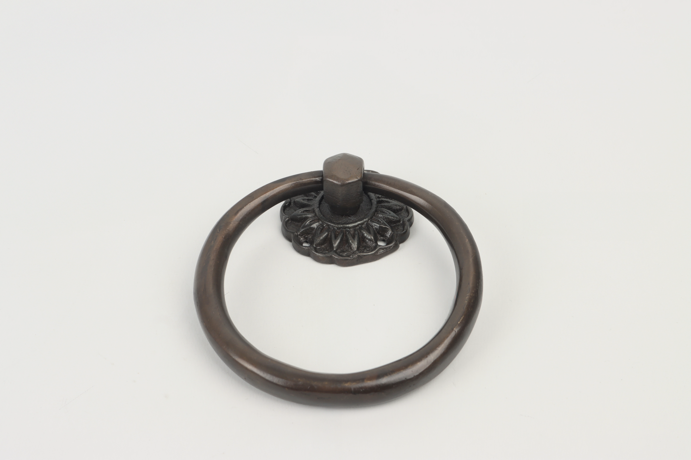 Close-up of a decorative metal ring door knocker mounted on a white background.