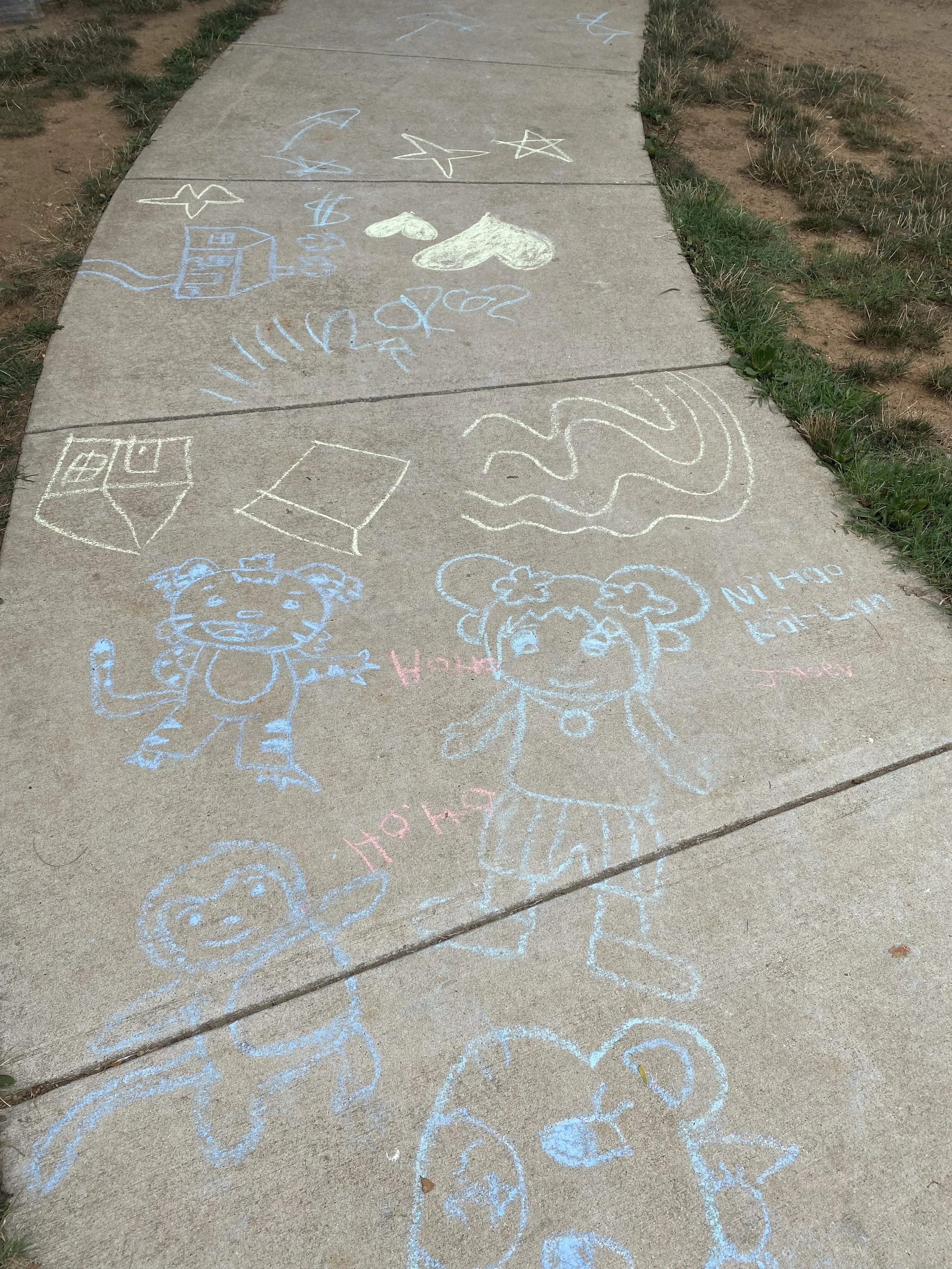 Colorful chalk drawings on a concrete sidewalk, including animals, characters, and various shapes and symbols.